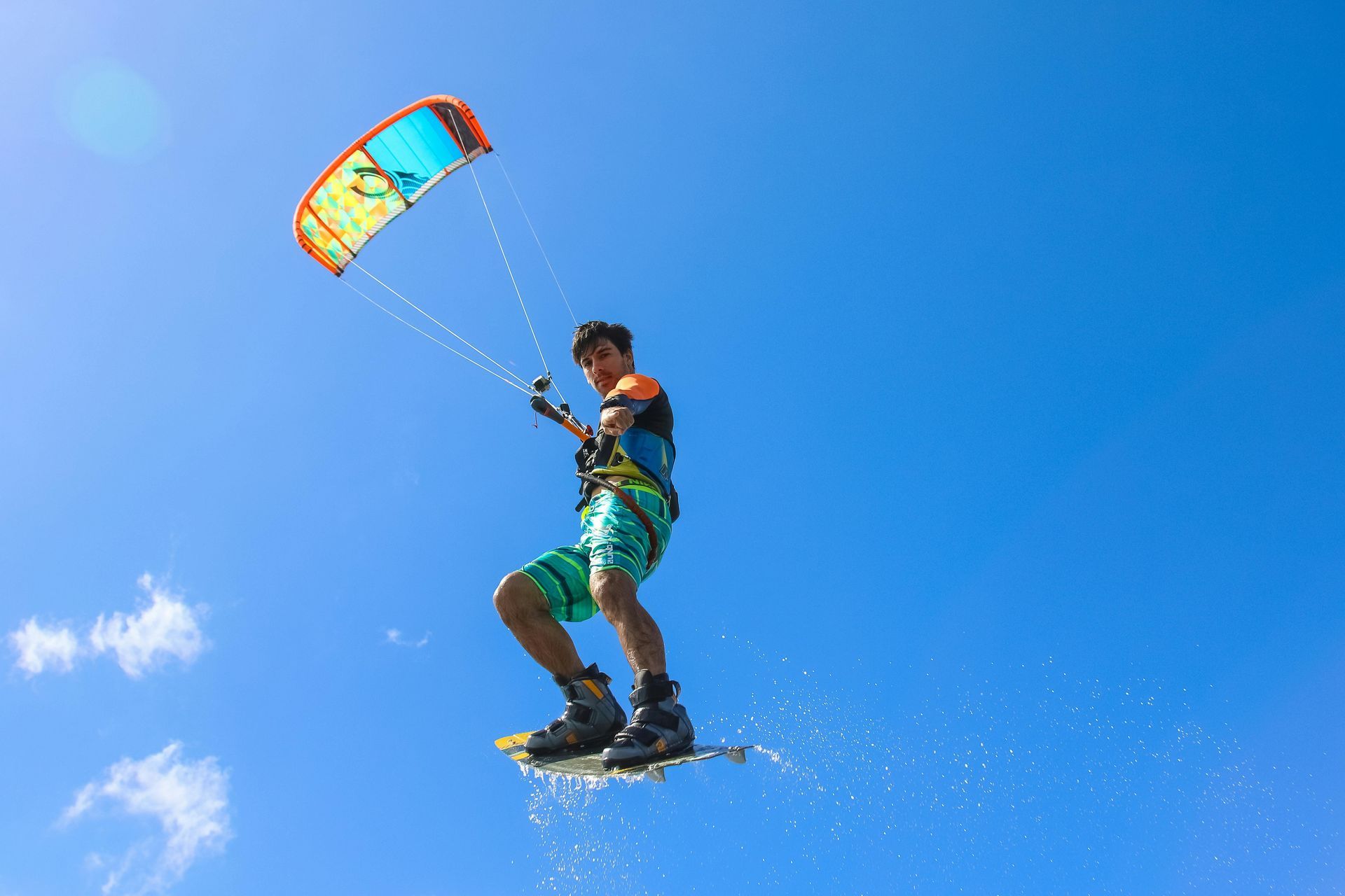 Un hombre está volando por el aire mientras monta una tabla de surf con una cometa.