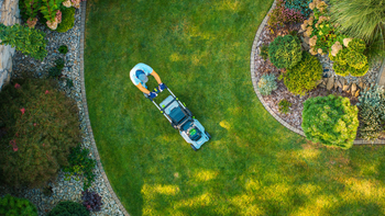 Overhead view of a kayak on a green lawn beside garden paths and shrubs