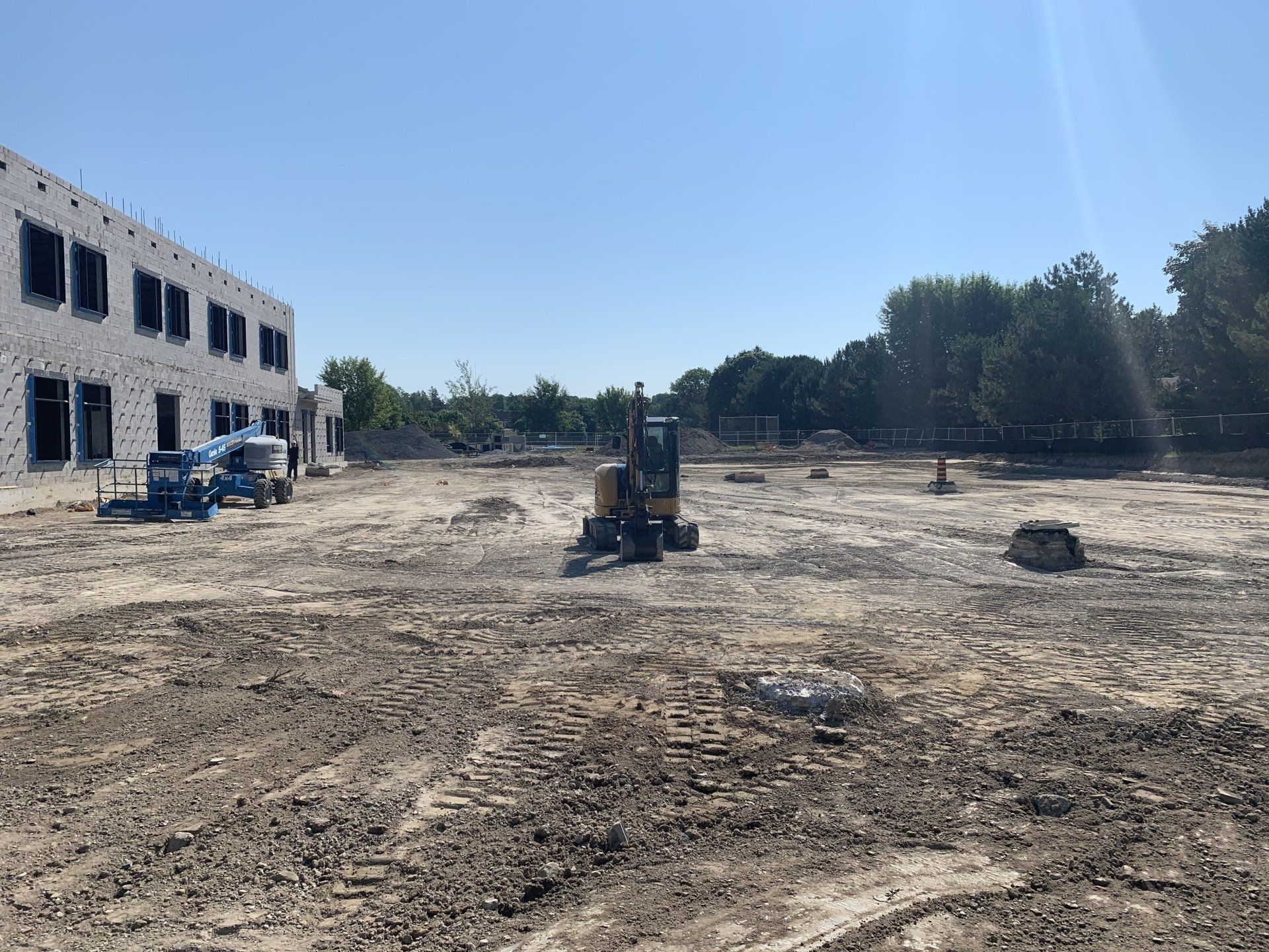 A construction site with a building in the background and a bulldozer in the foreground.