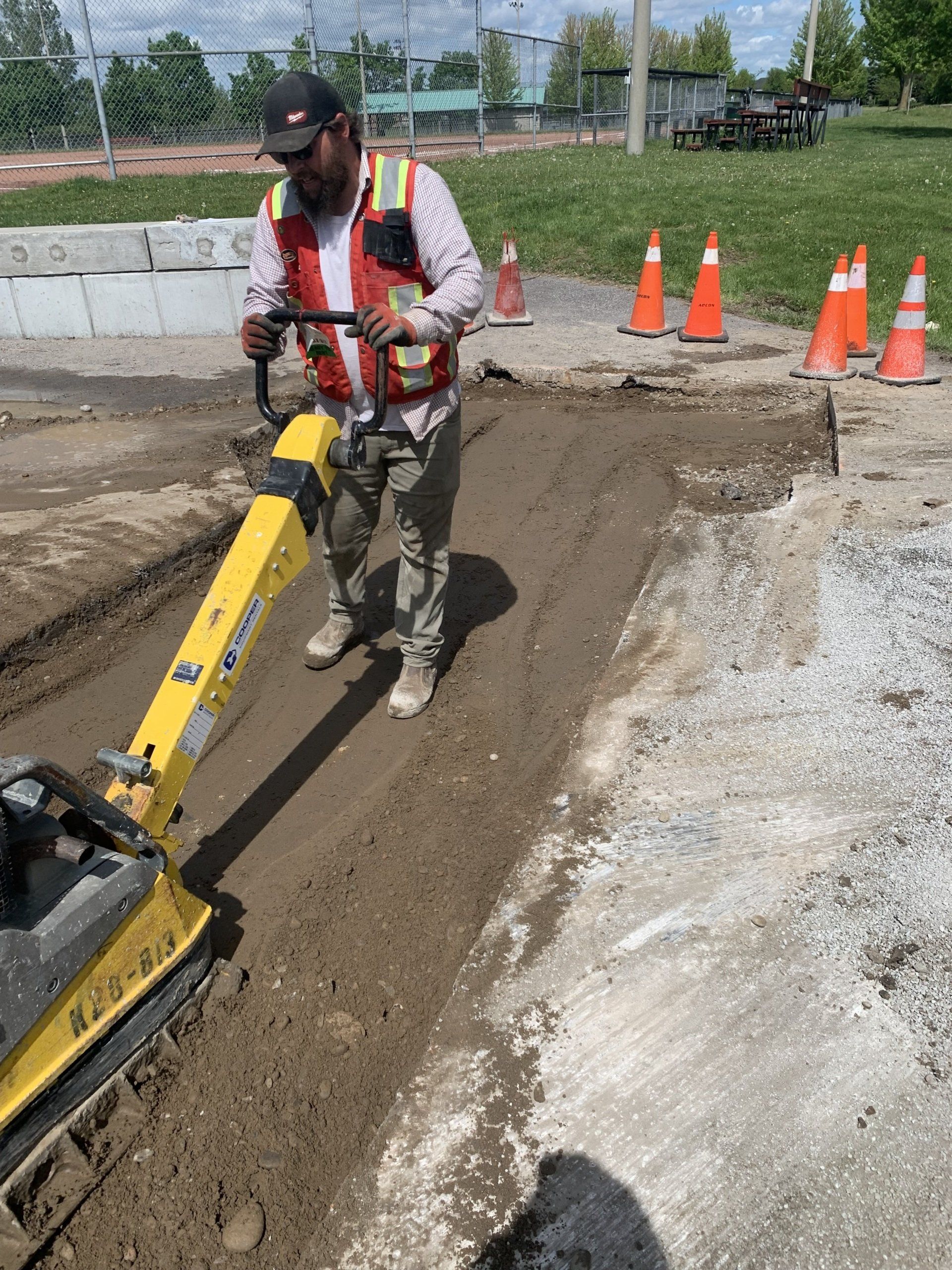 A man is using a yellow machine to level the ground.