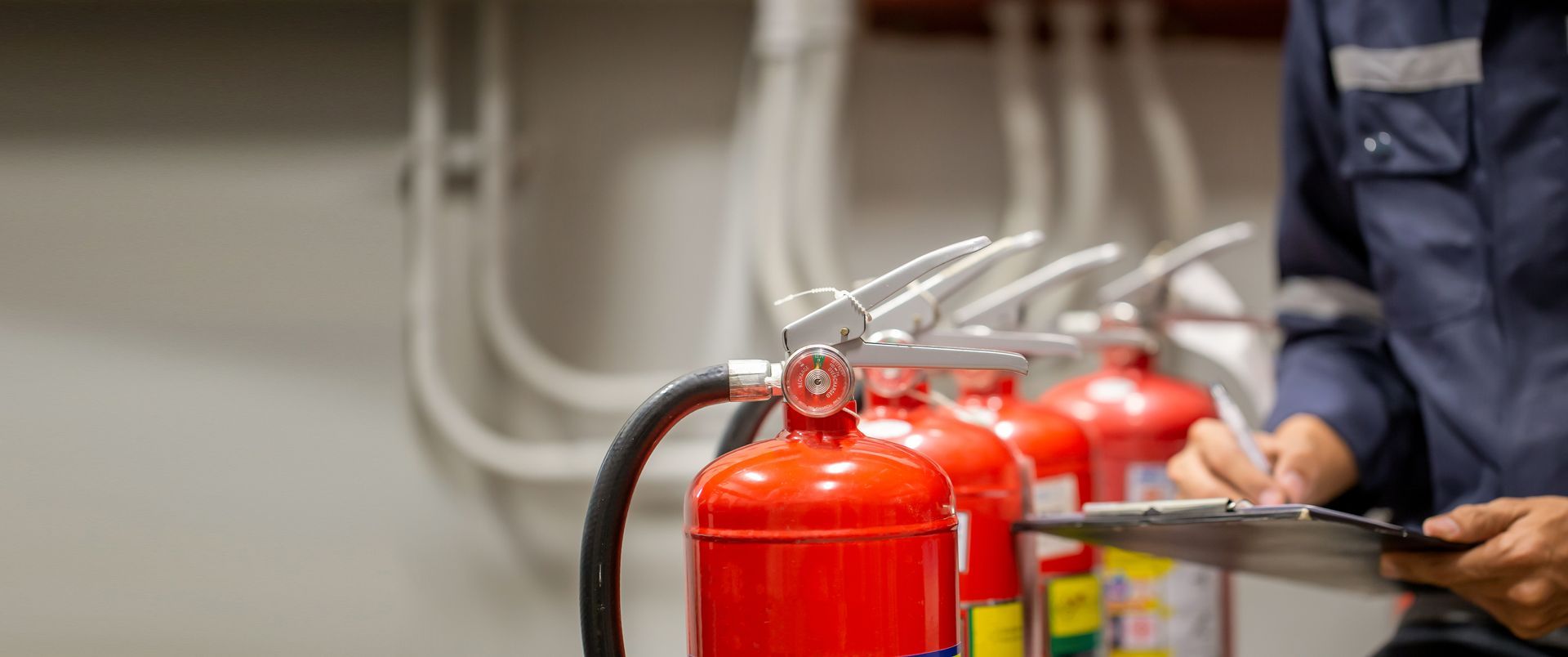 Row of fire extinguishers with an inspector checking a clipboard nearby.