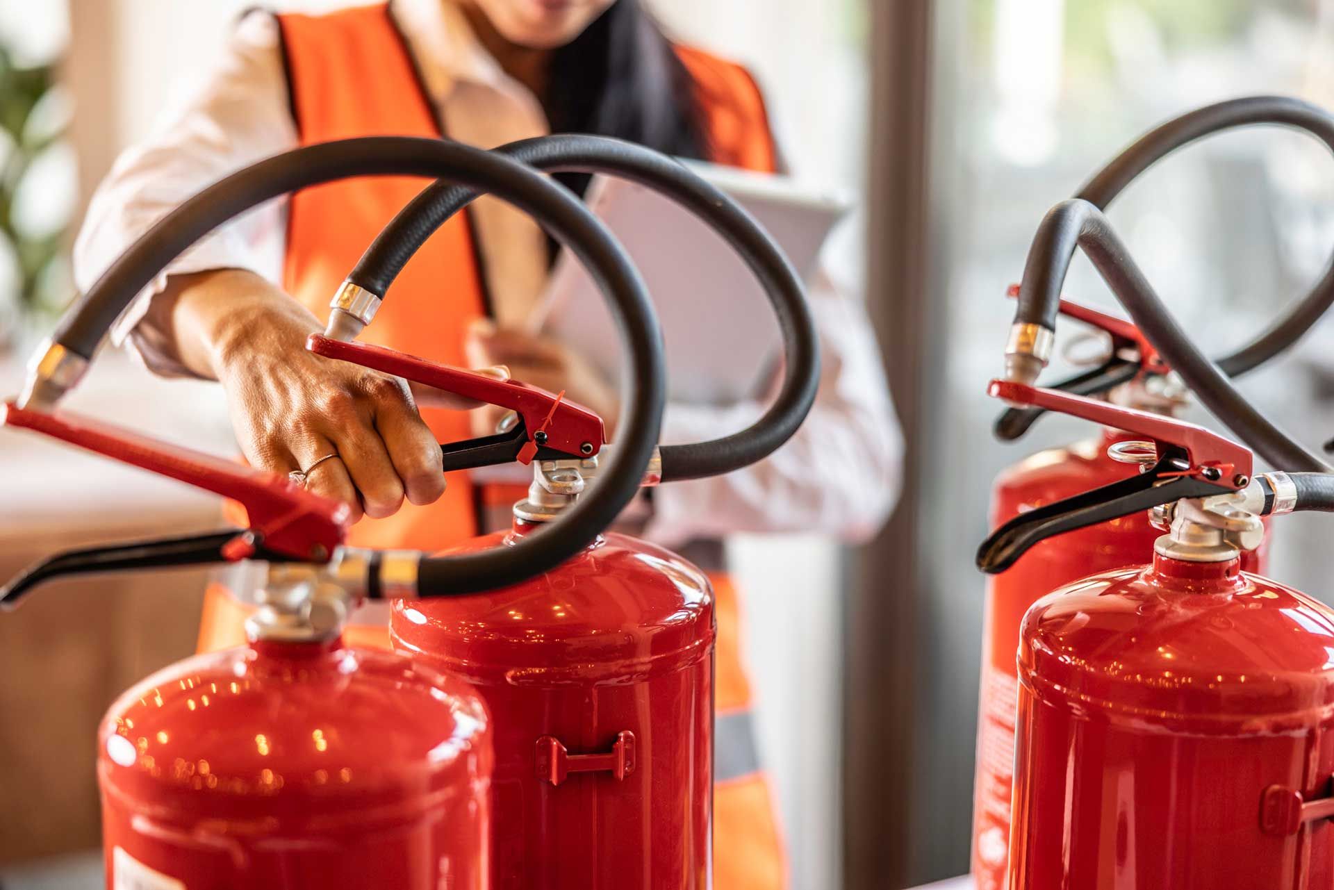A female safety inspector checks fire extinguishers.