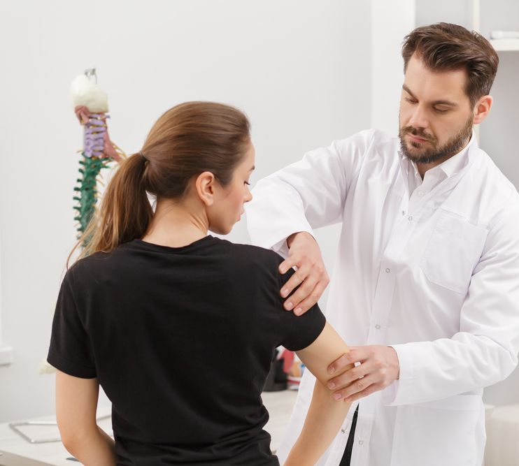 Doctor Examining A Woman's Arm In A Medical Office — Integrate Health In Ooralea, QLD