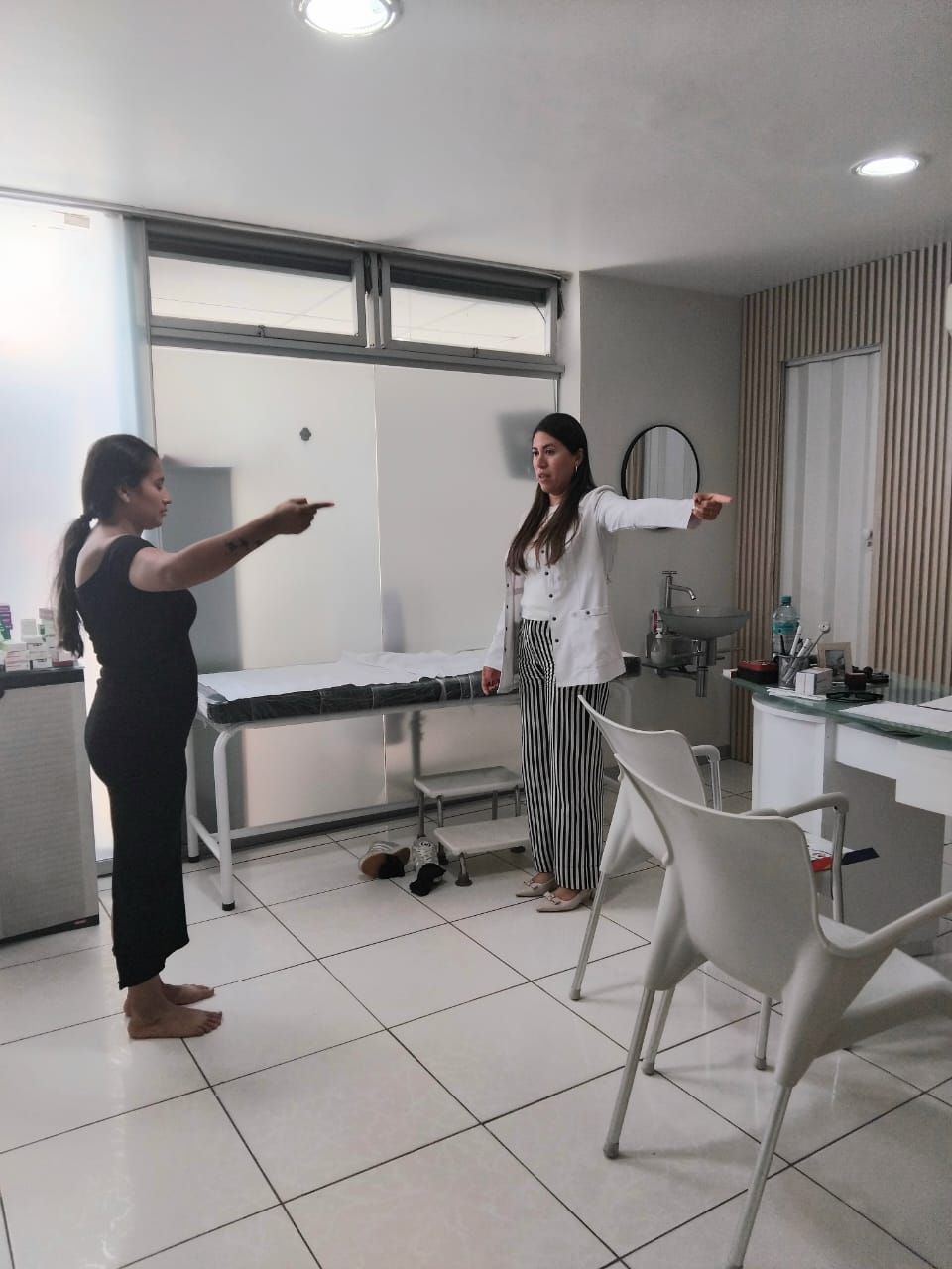 Mujer vestida de negro y médico haciendo ejercicios de brazos en una sala de la clínica.