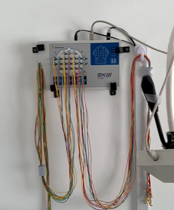 Dispositivo BCI de pared con cables multicolores, parte de un equipo médico. Los cables cuelgan hacia el suelo.