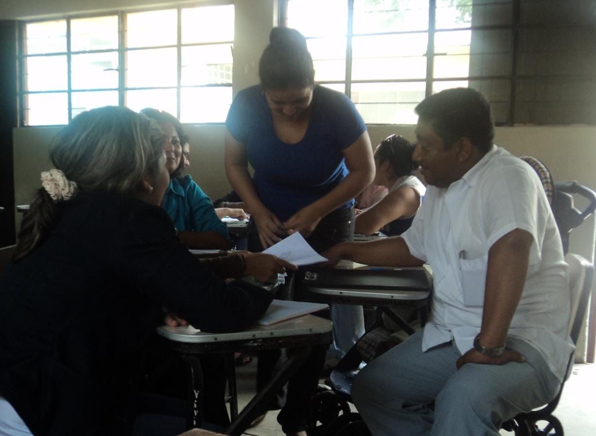 Personas revisando documentos en un escritorio en una habitación con ventanas