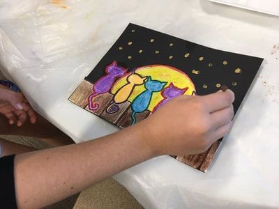 Child painting a colorful nighttime scene with people under a moon and stars