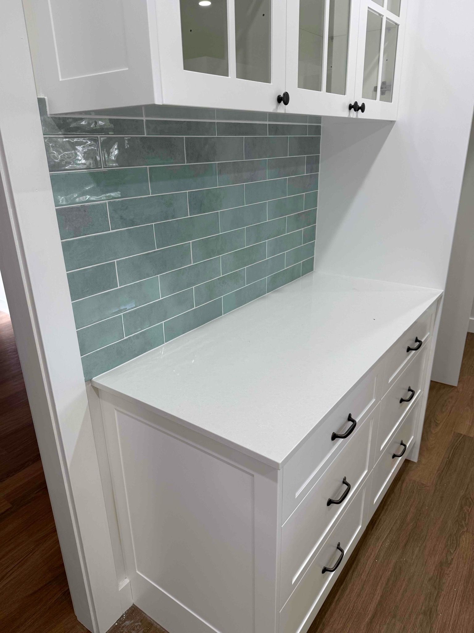 White Cabinetry With Glass-Front Upper Cabinet Drawer and Subway Tile Backsplash — Seeto Tiling in Nelson Bay, NSW