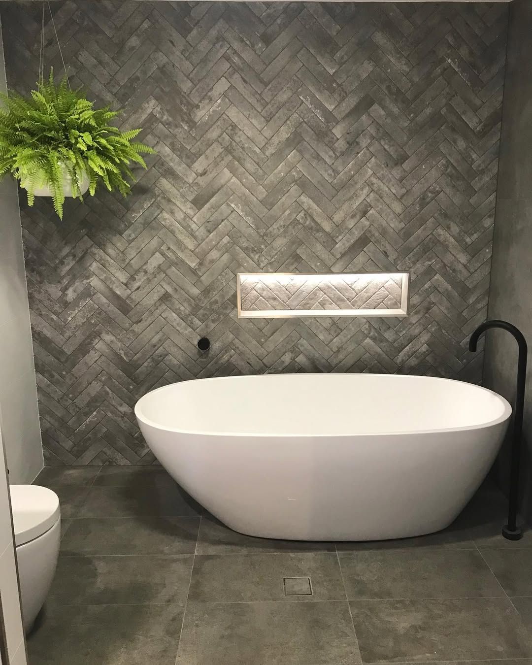 A Bathroom With a White Tub Gray Herringbone Tile Wall and Hanging Fern — Seeto Tiling in Fingal Bay, NSW