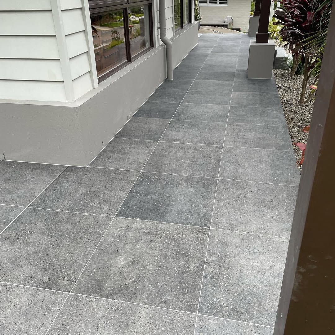 Grey Tiled Walkway Alongside a Building With White Siding and a Dark Window — Seeto Tiling in Fingal Bay, NSW