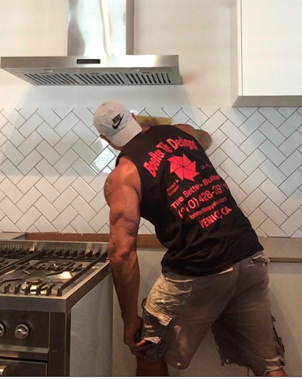 A man is wiping down tiles in kitchen once completed — Seeto Tiling in Raymond Terrace, NSW