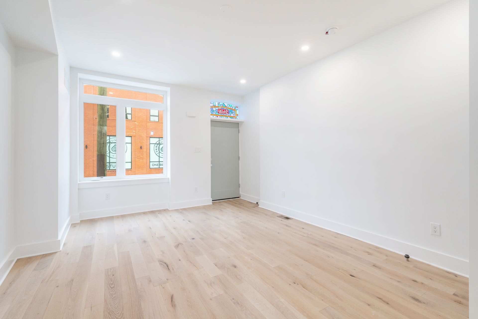 An empty living room with hardwood floors and white walls.