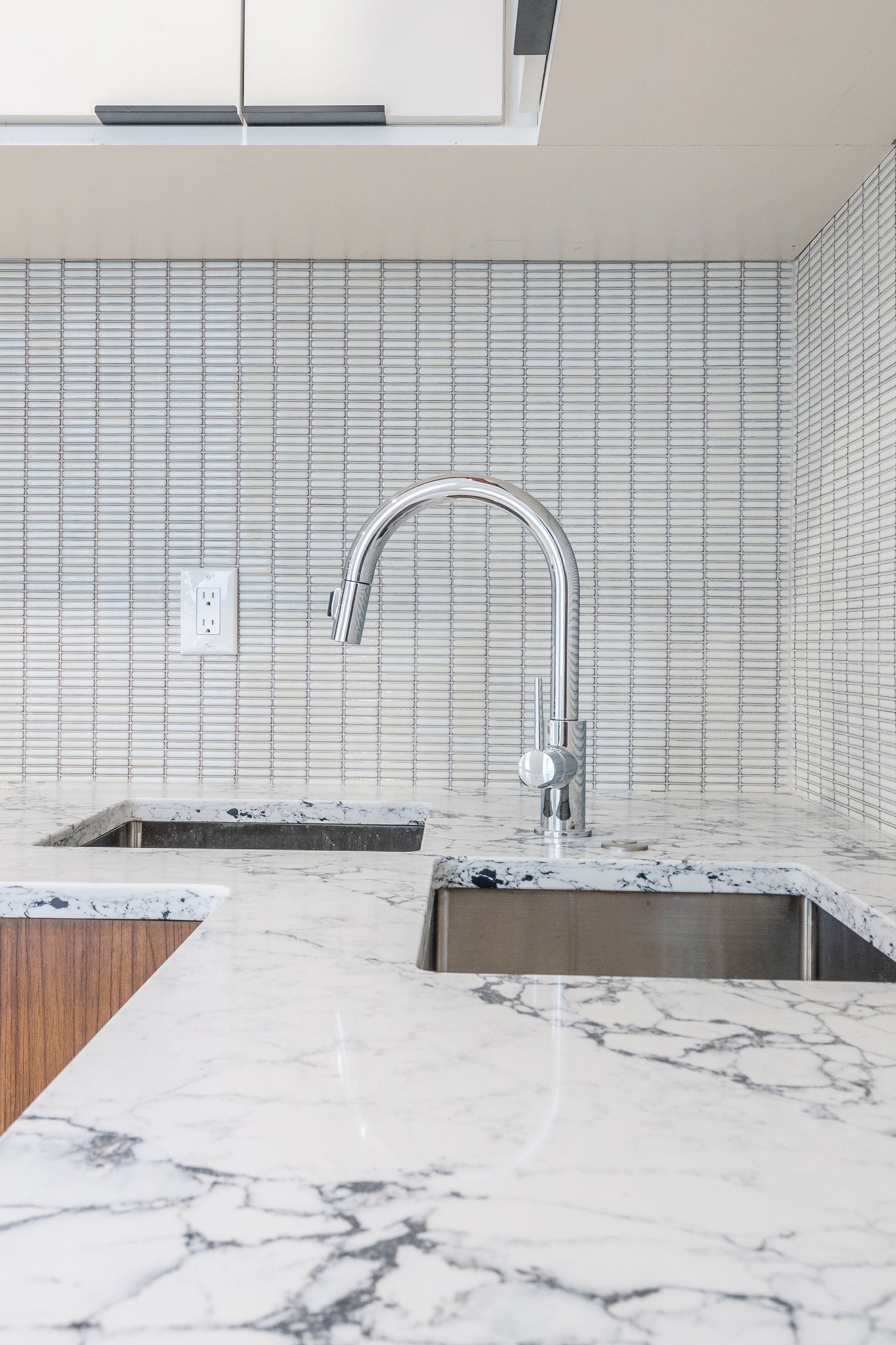 A kitchen with a sink and a faucet on a marble counter top.
