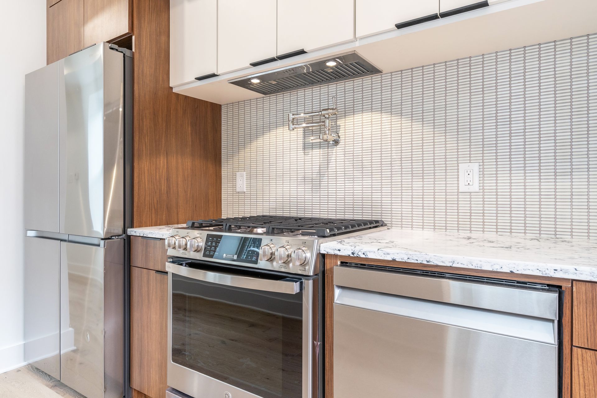 A kitchen with stainless steel appliances and a refrigerator.