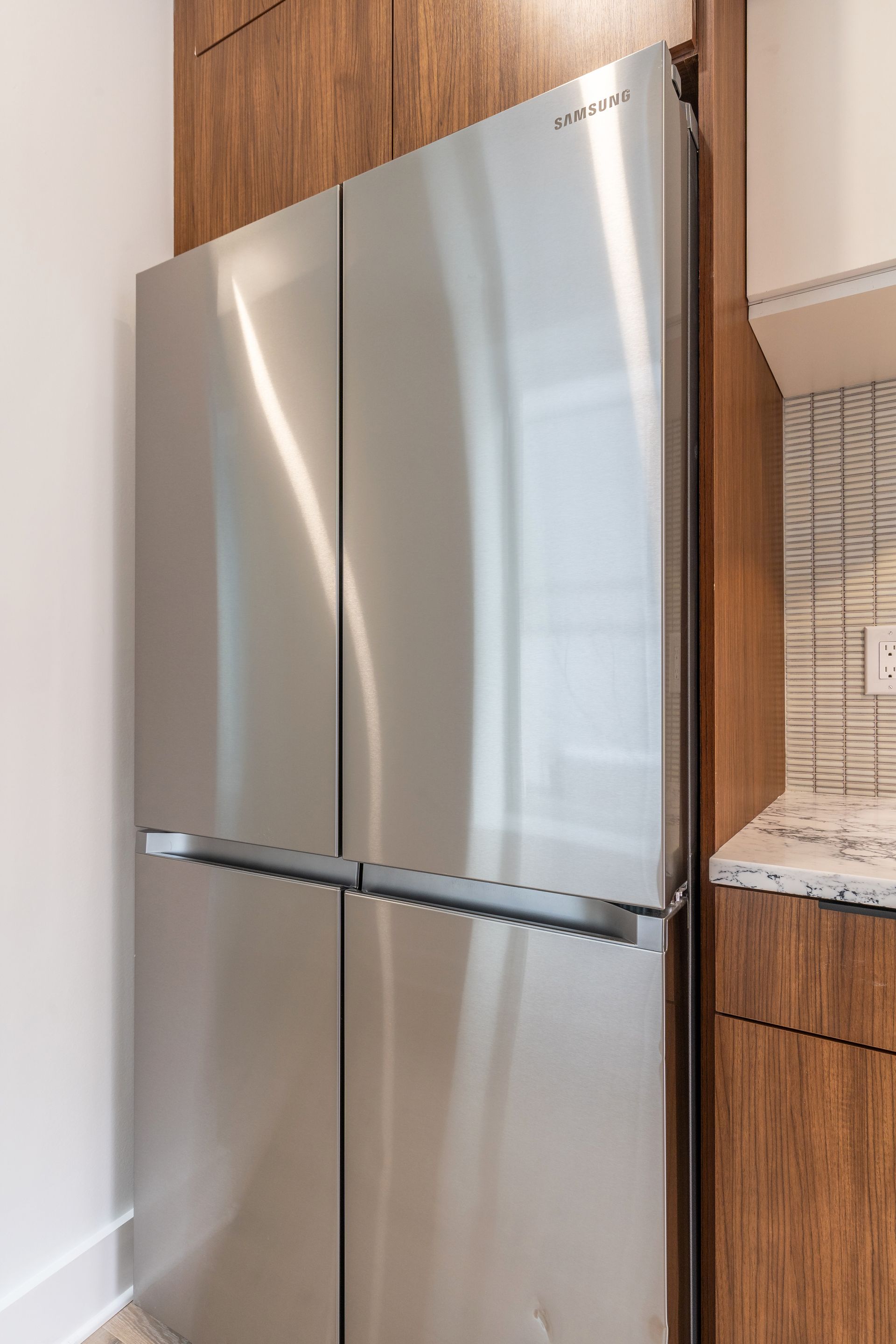 A stainless steel refrigerator is sitting in a kitchen next to a counter.
