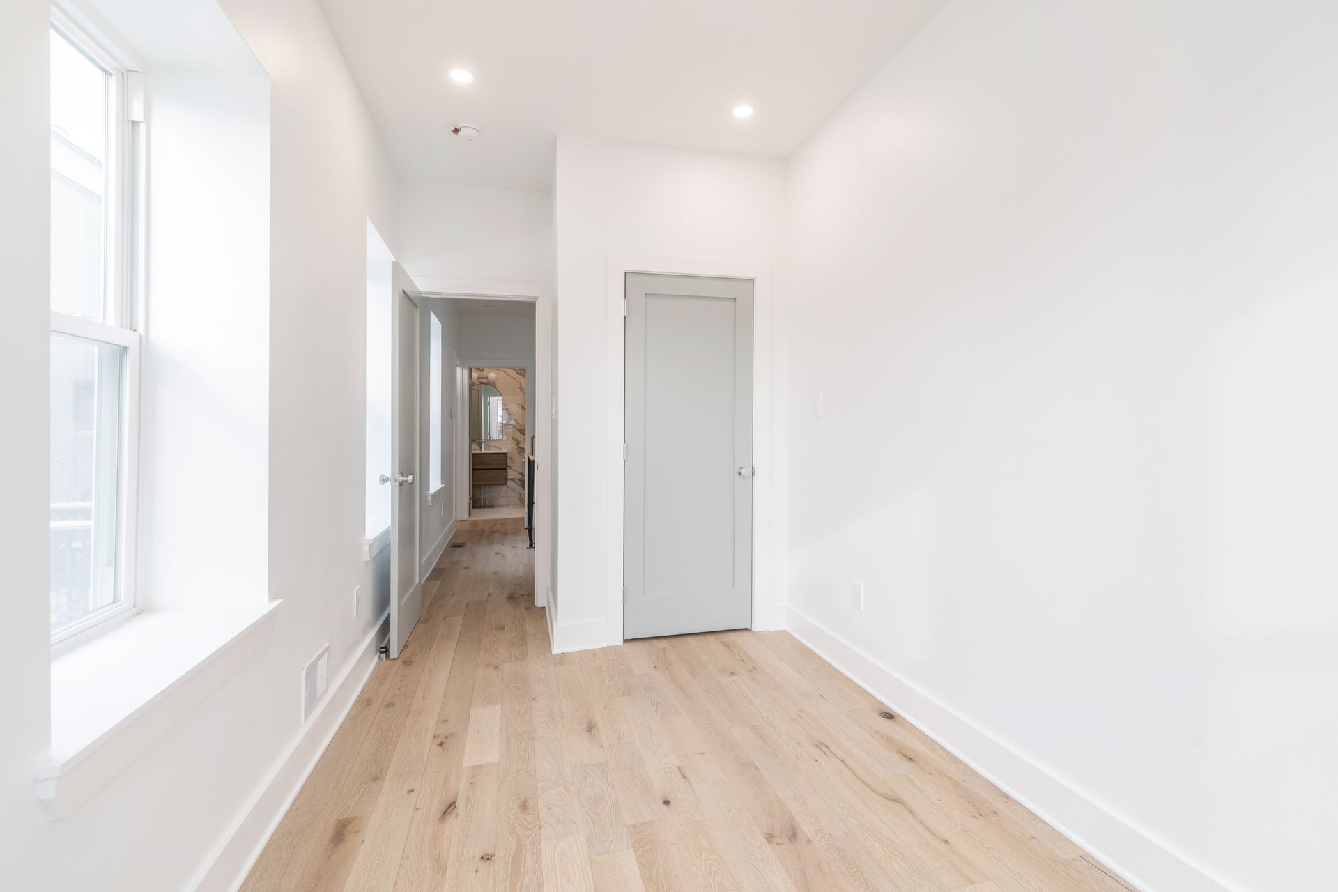 An empty room with hardwood floors and white walls.