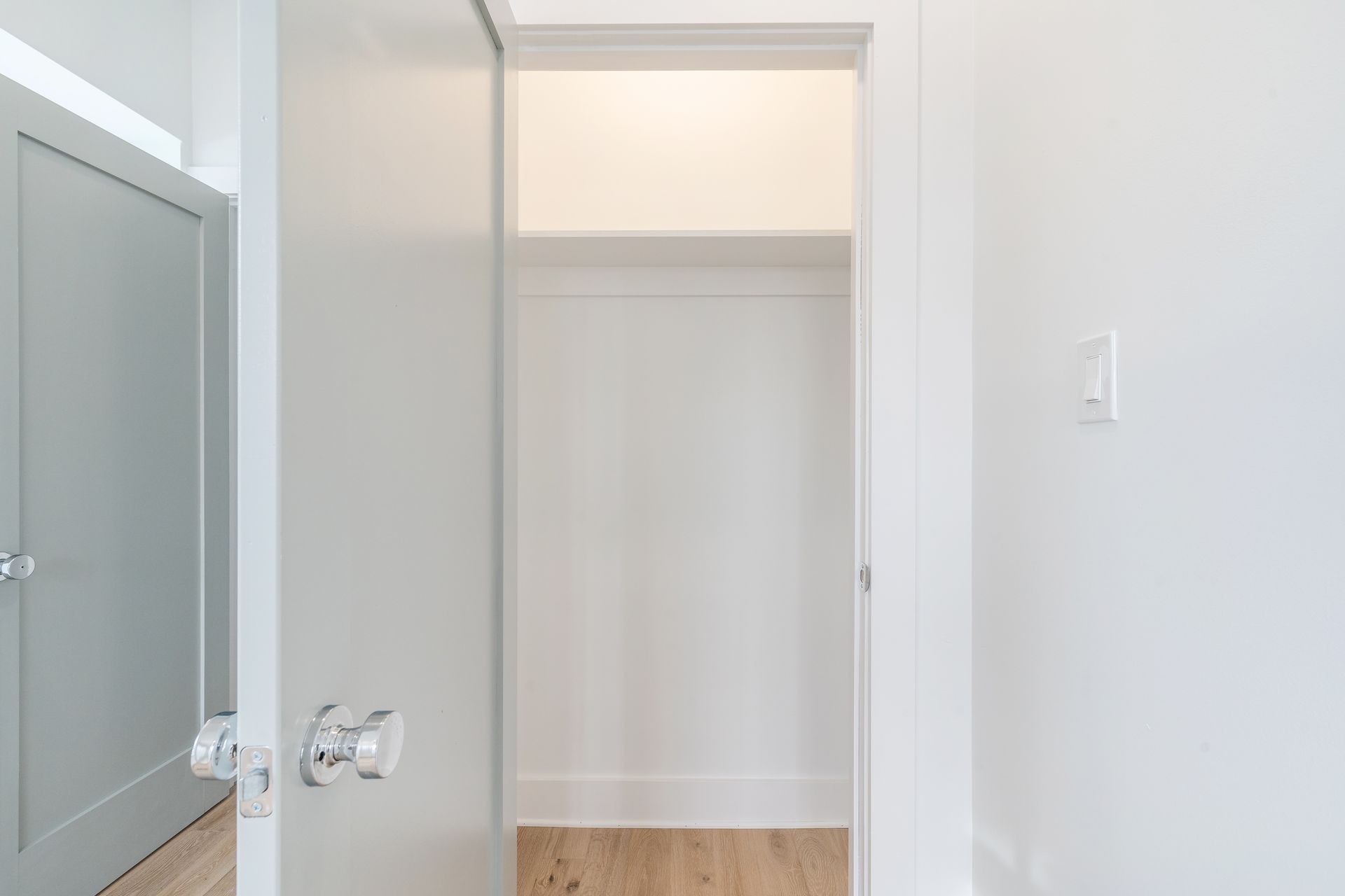 An empty closet in a house with a wooden floor and white walls.