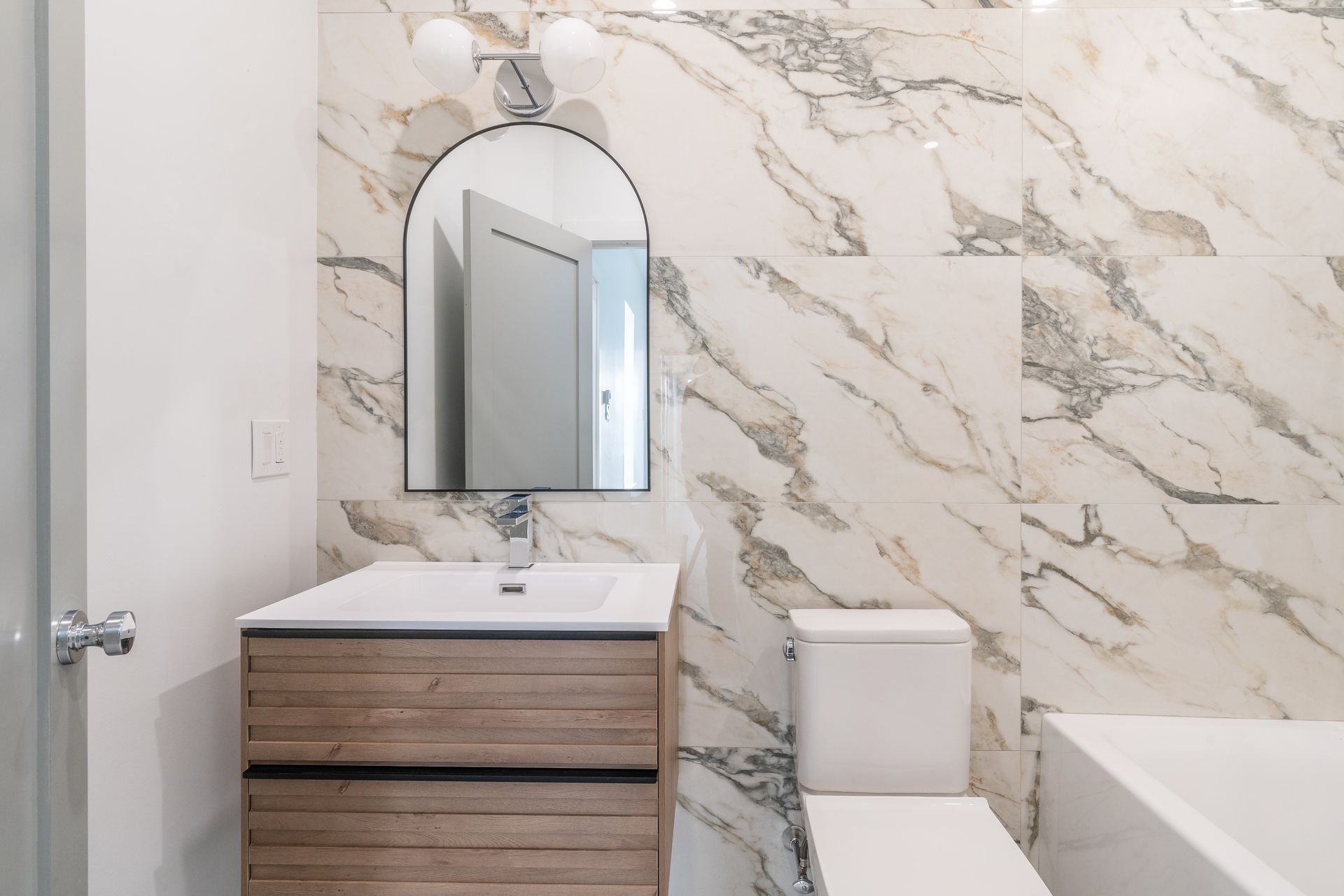 A bathroom with marble tiles , a sink , toilet , and bathtub.