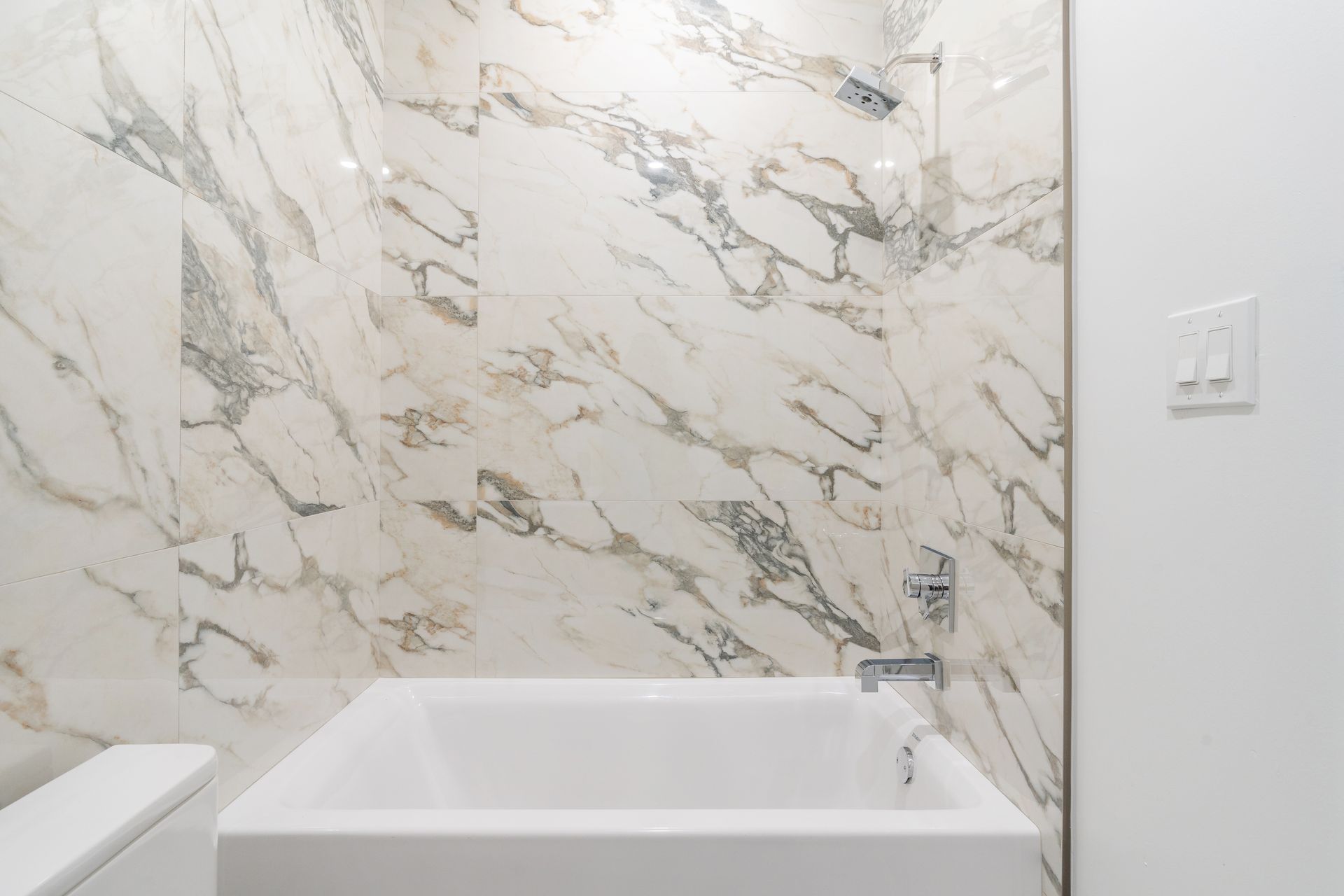 A bathroom with a marble wall and a bathtub.