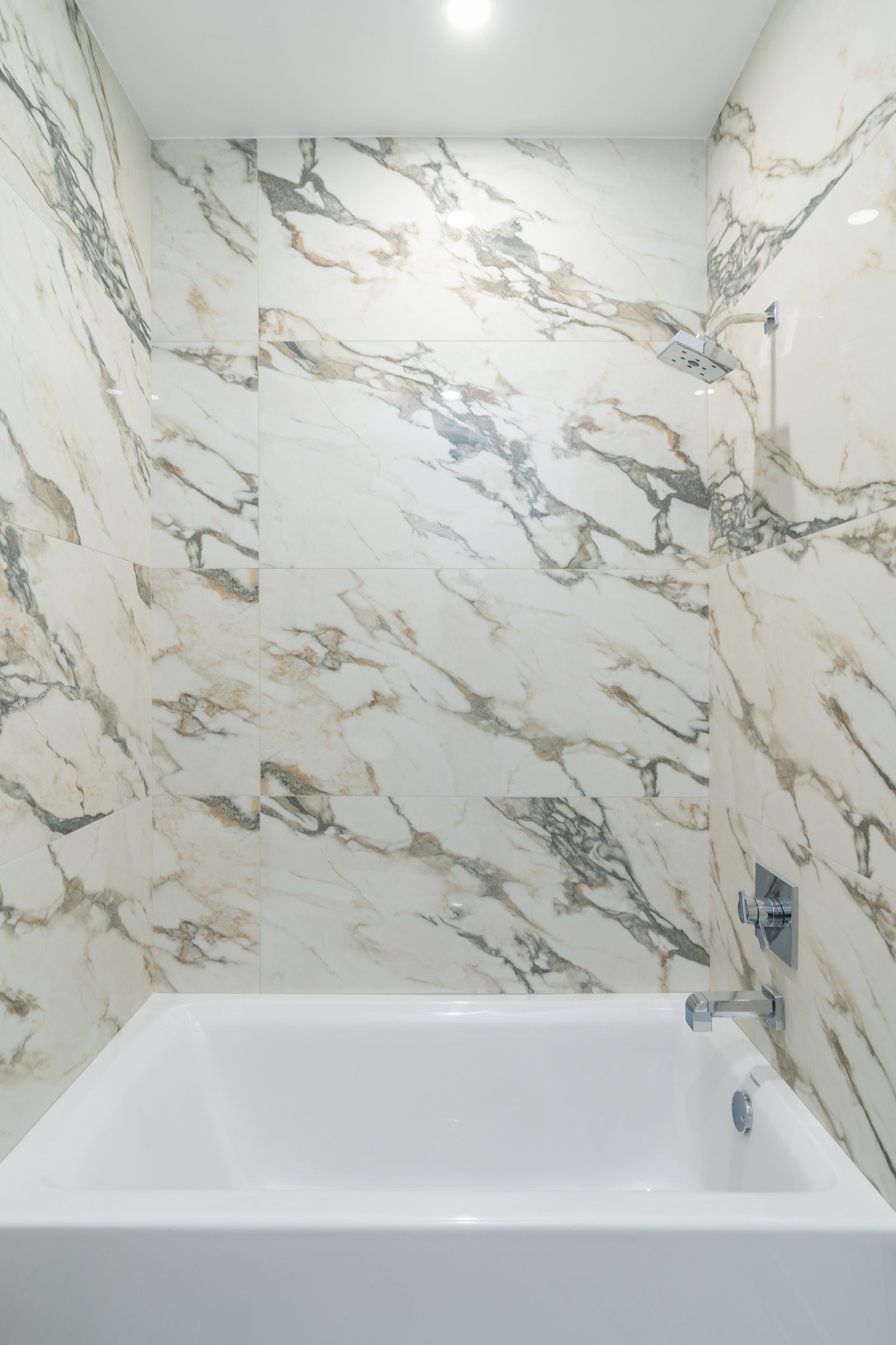 A bathroom with marble walls and a bathtub.
