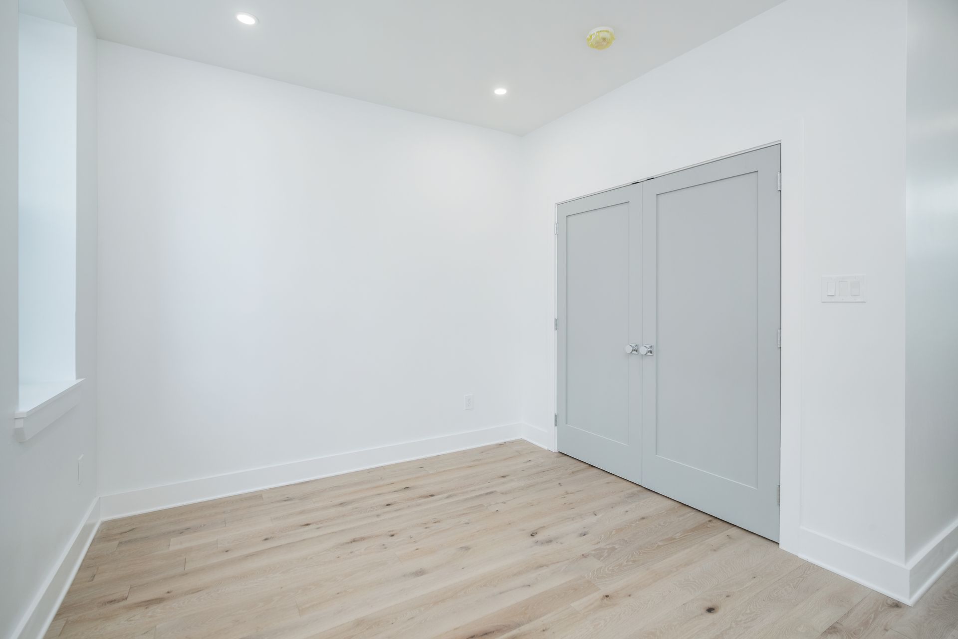 An empty room with hardwood floors and white walls.