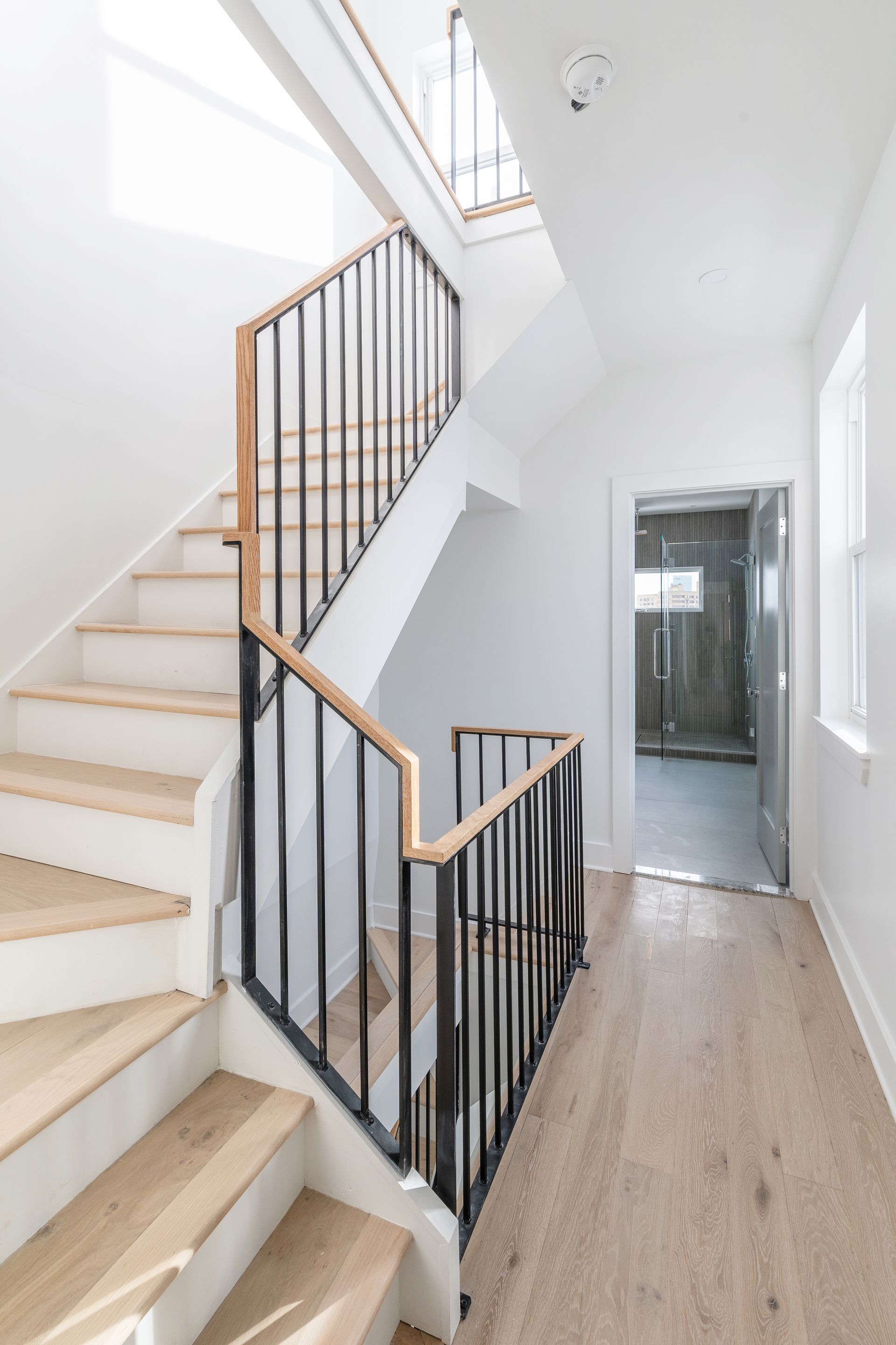 A staircase with wooden steps and a metal railing in a hallway.