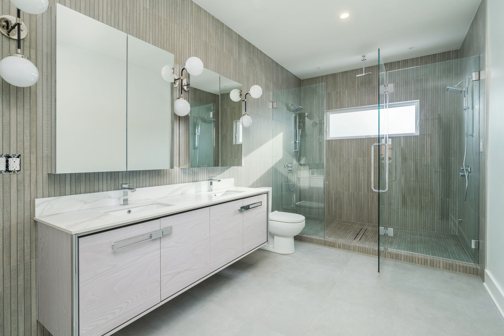 A bathroom with a toilet , sink , mirror and walk in shower.