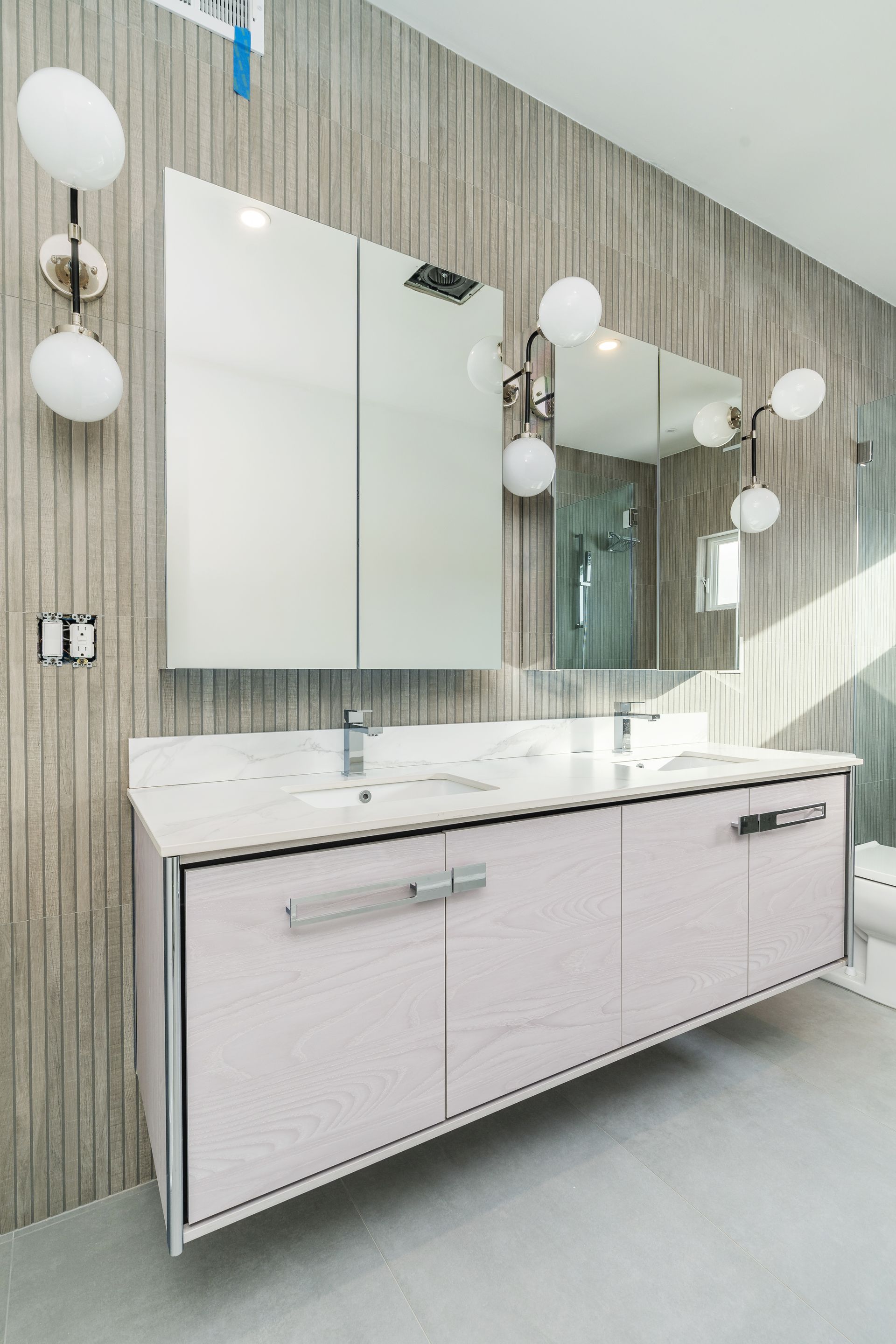 A bathroom with two sinks , a mirror and a toilet.