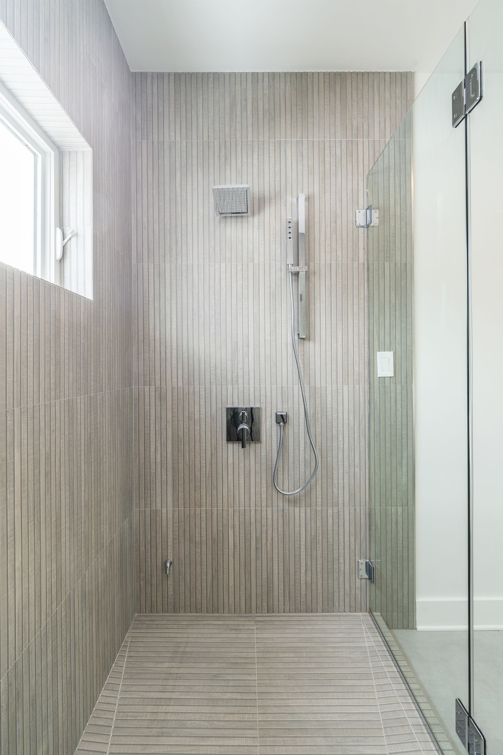 A bathroom with a walk in shower and a window.