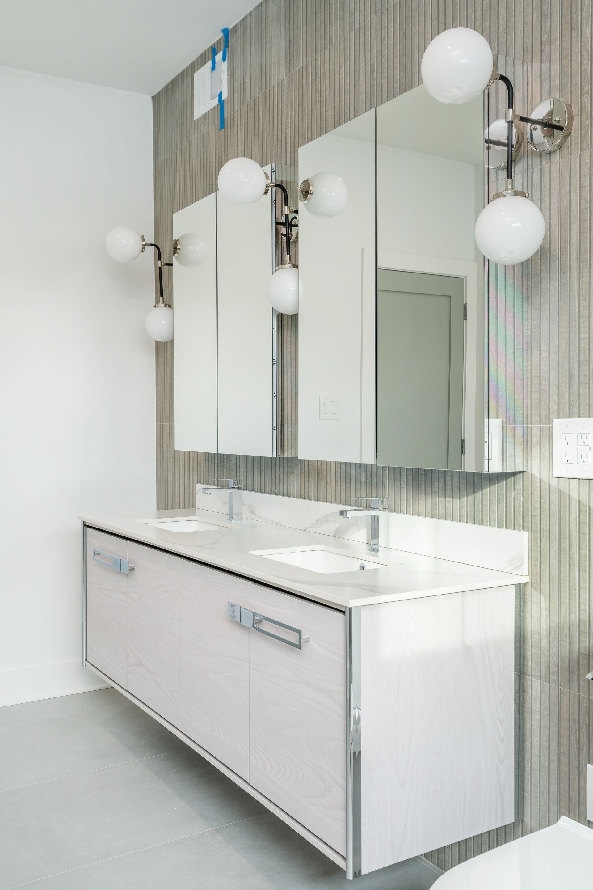 A bathroom with two sinks , two mirrors and a toilet.
