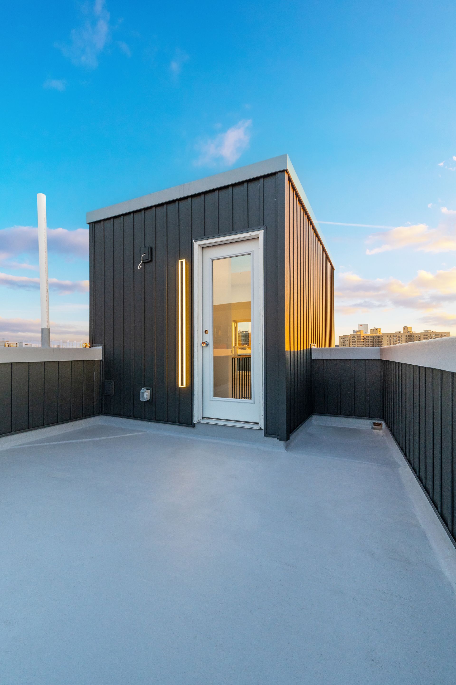 A small black building with a white door on the roof of a building.