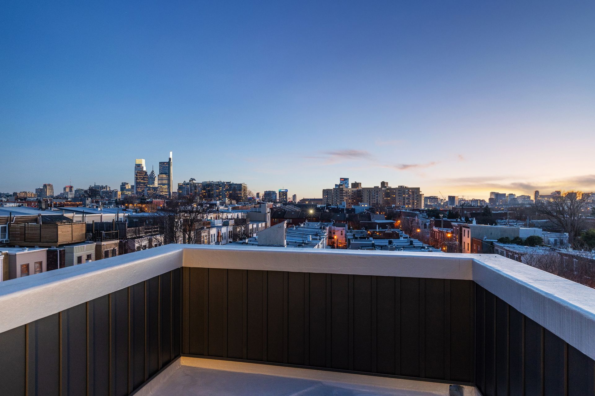 A balcony with a view of a city skyline at sunset.