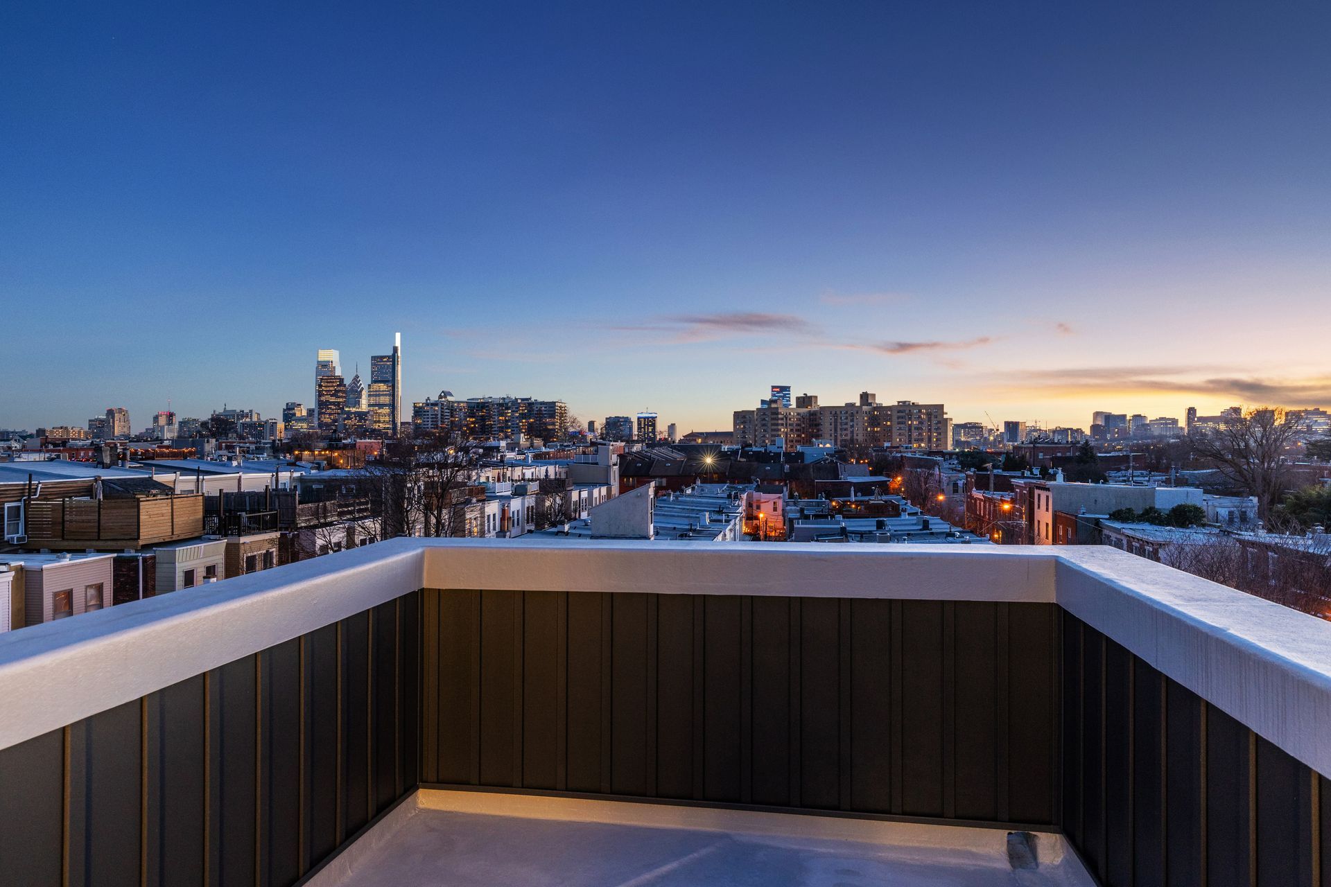 A balcony with a view of the city skyline at sunset.