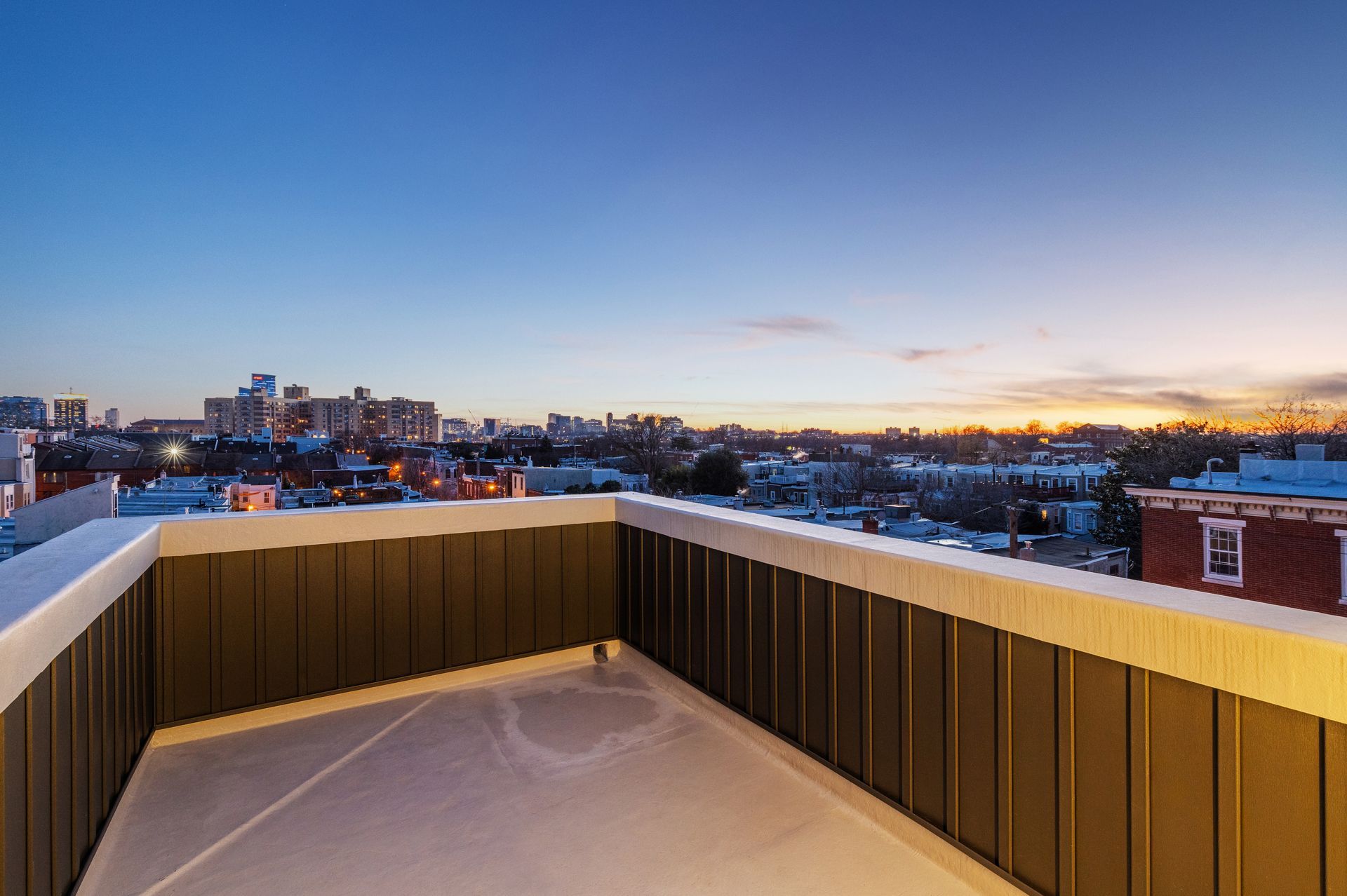 A rooftop deck with a view of a city at sunset.