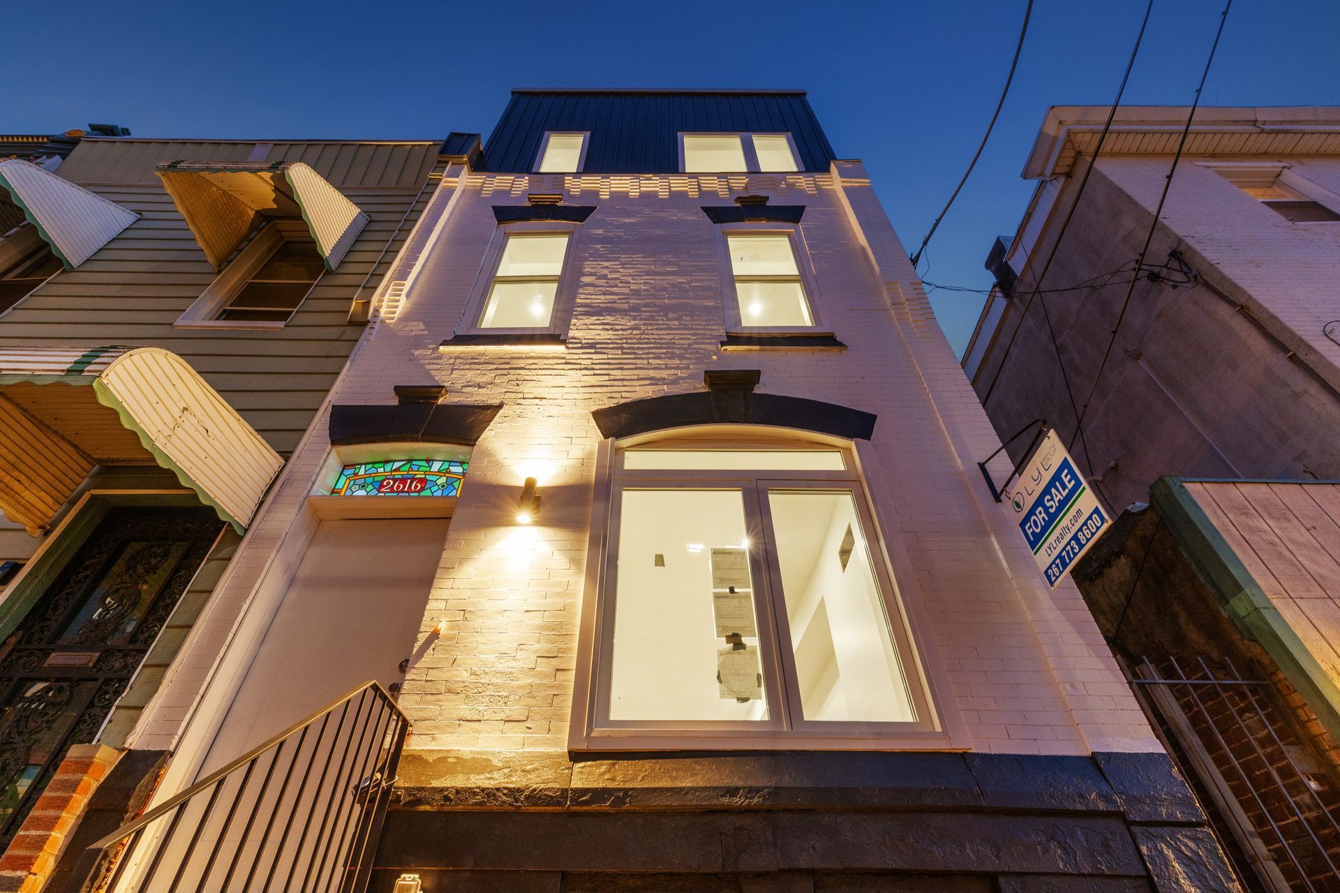 The front of a building with a for sale sign on the side of it.