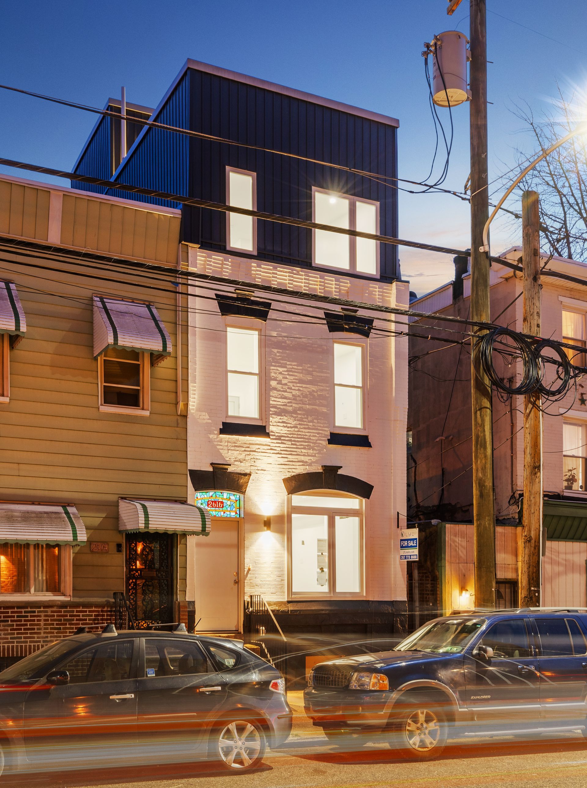 Cars are driving down a street in front of a building at night.