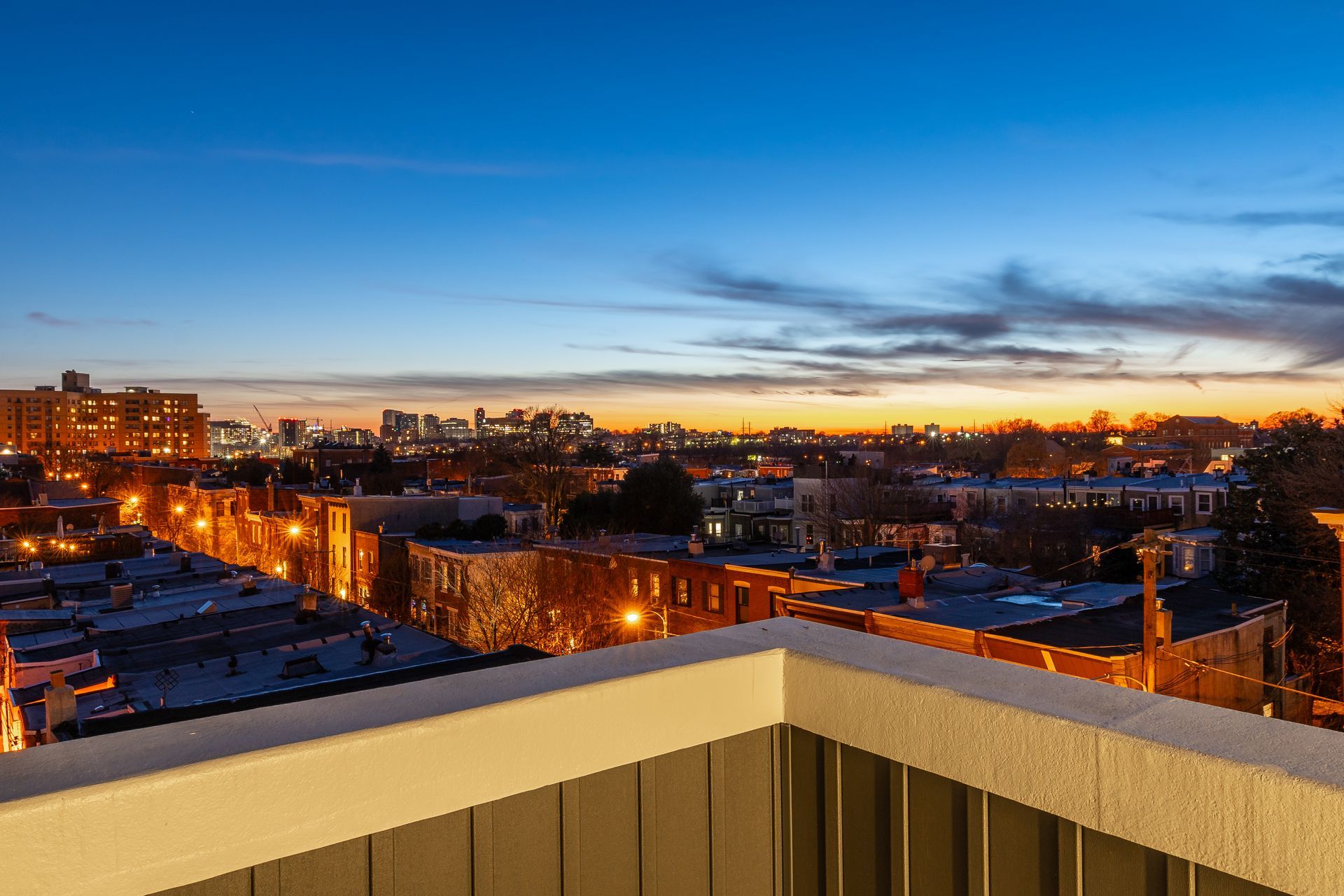A view of a city from a balcony at sunset.