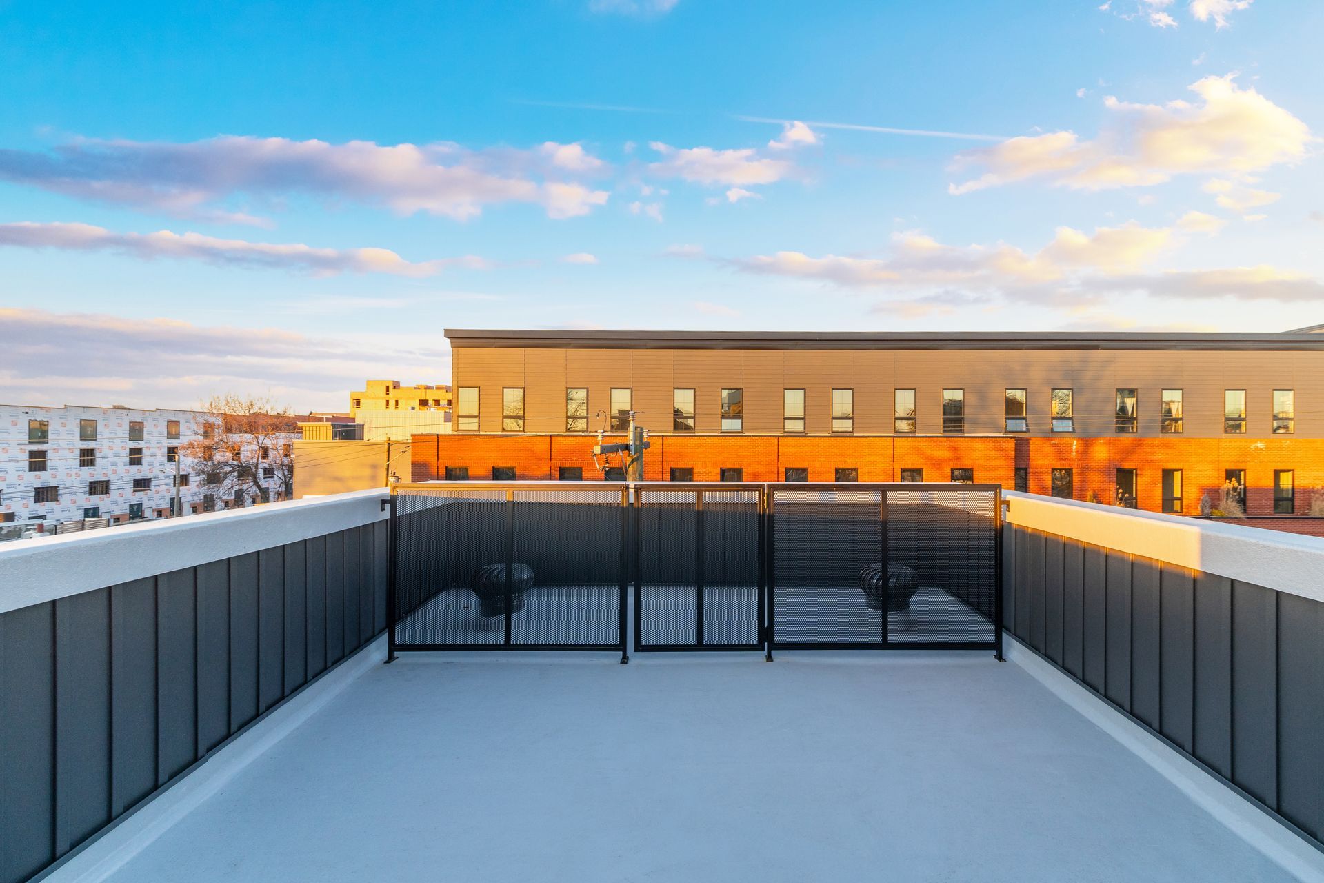 A rooftop deck with a fence and a view of a building.