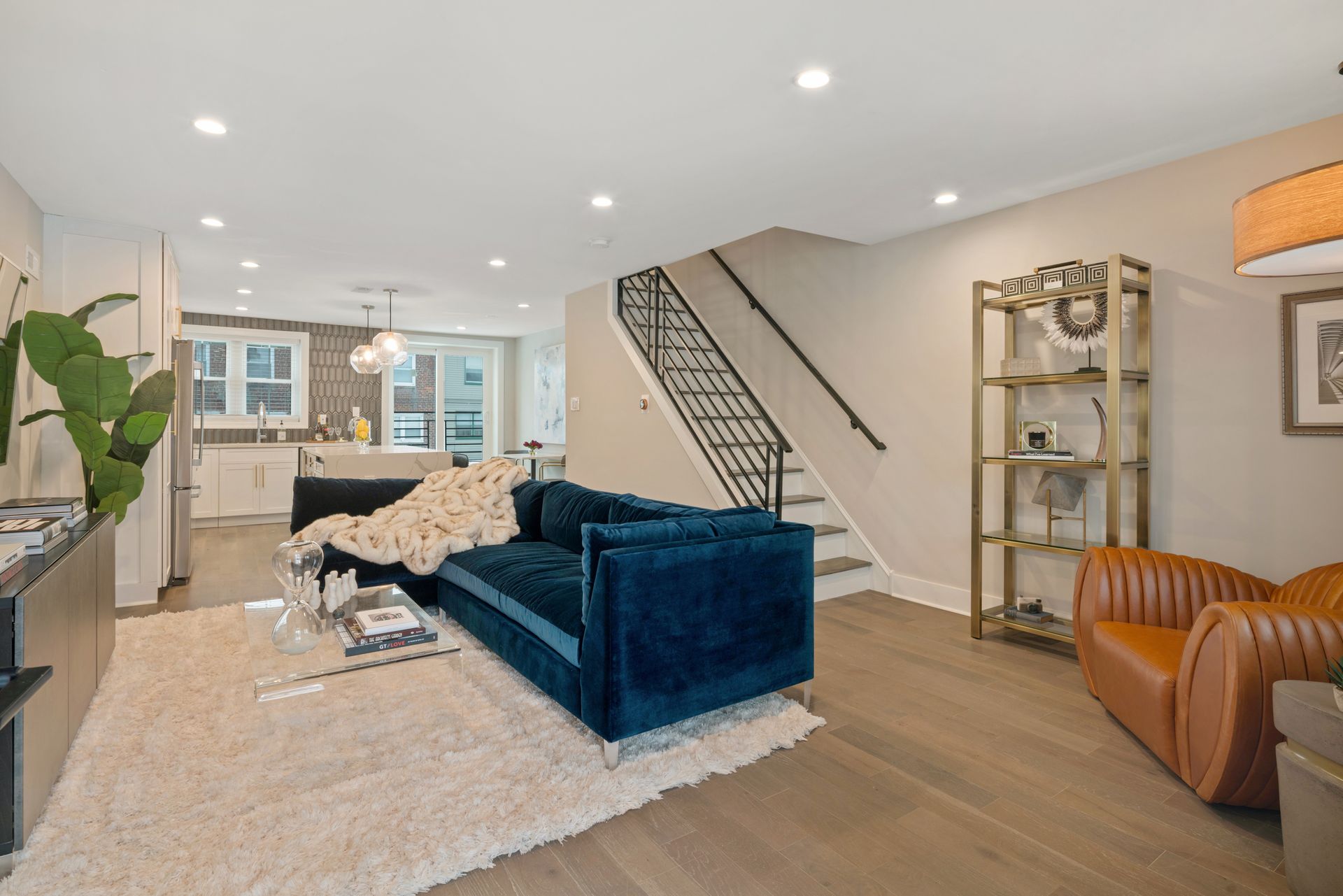 A living room with a blue couch , chairs , and stairs.
