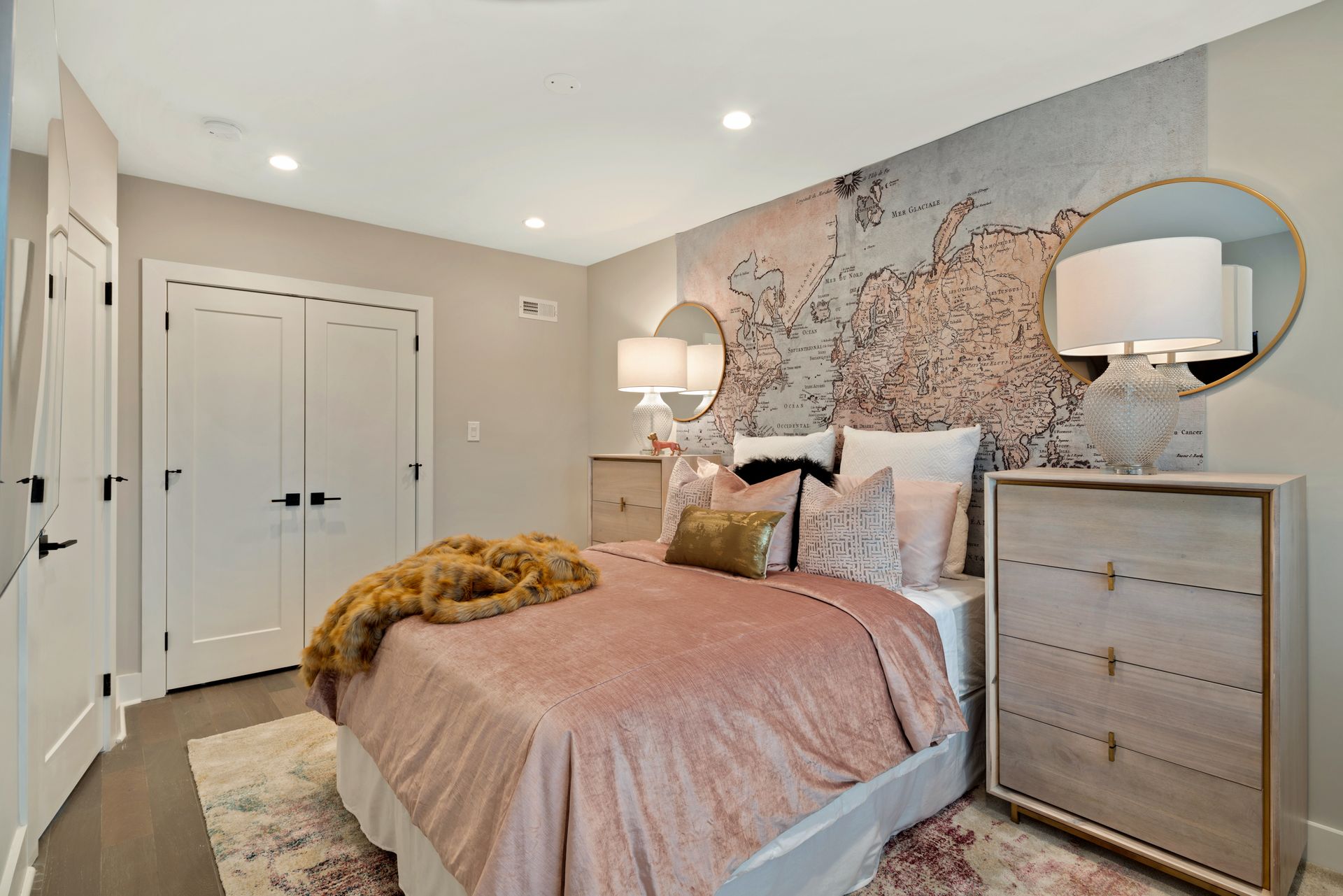 A bedroom with a bed , dresser , mirror and rug.