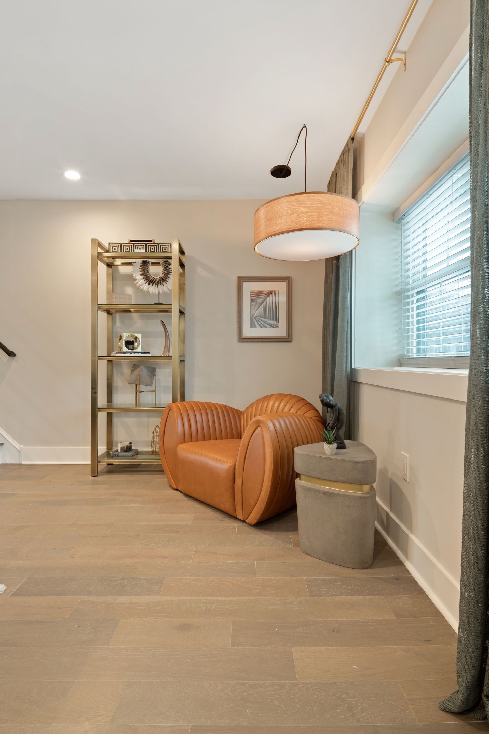 A living room with a chair , shelf , lamp and window.