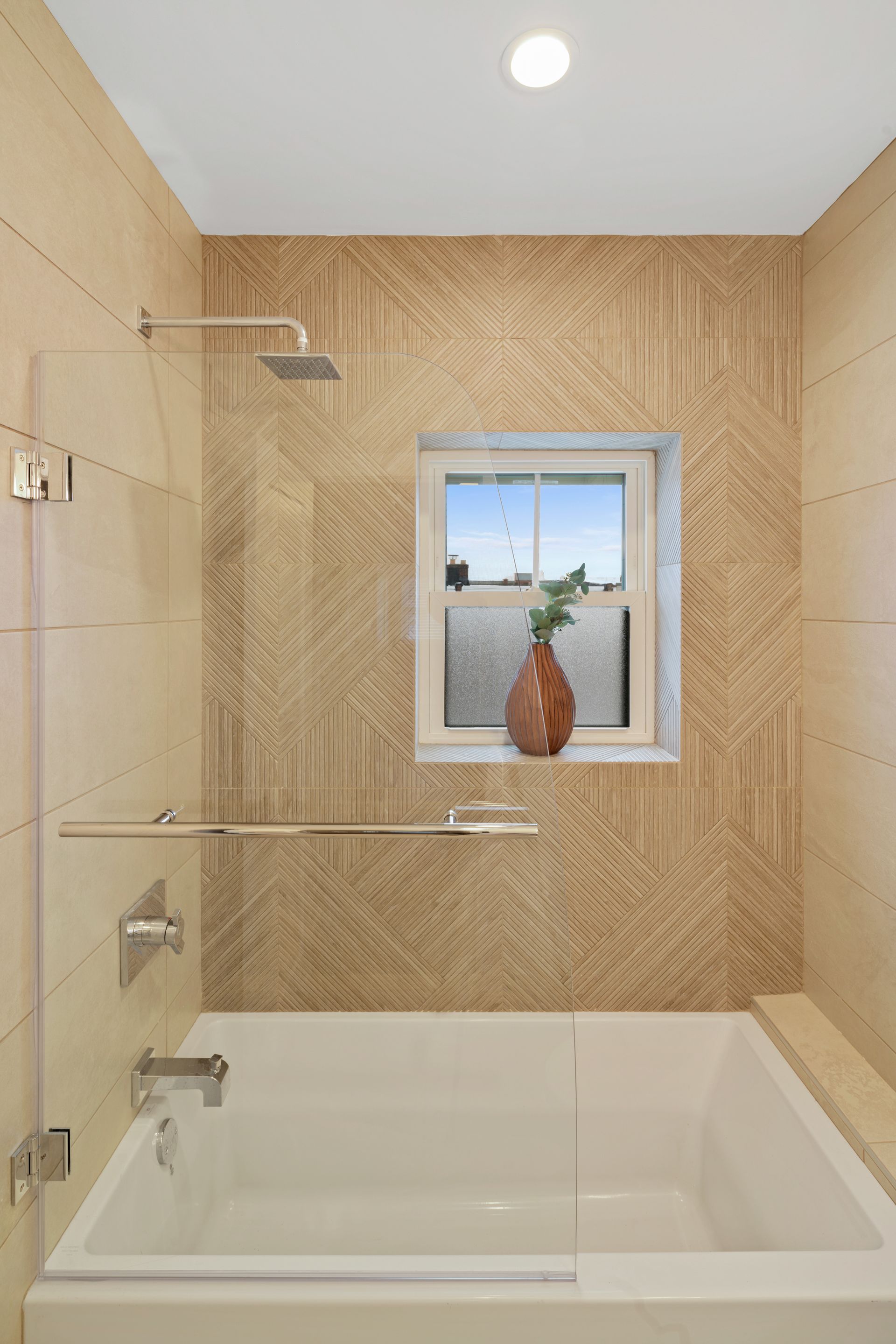 A bathroom with a tub , shower , and window.