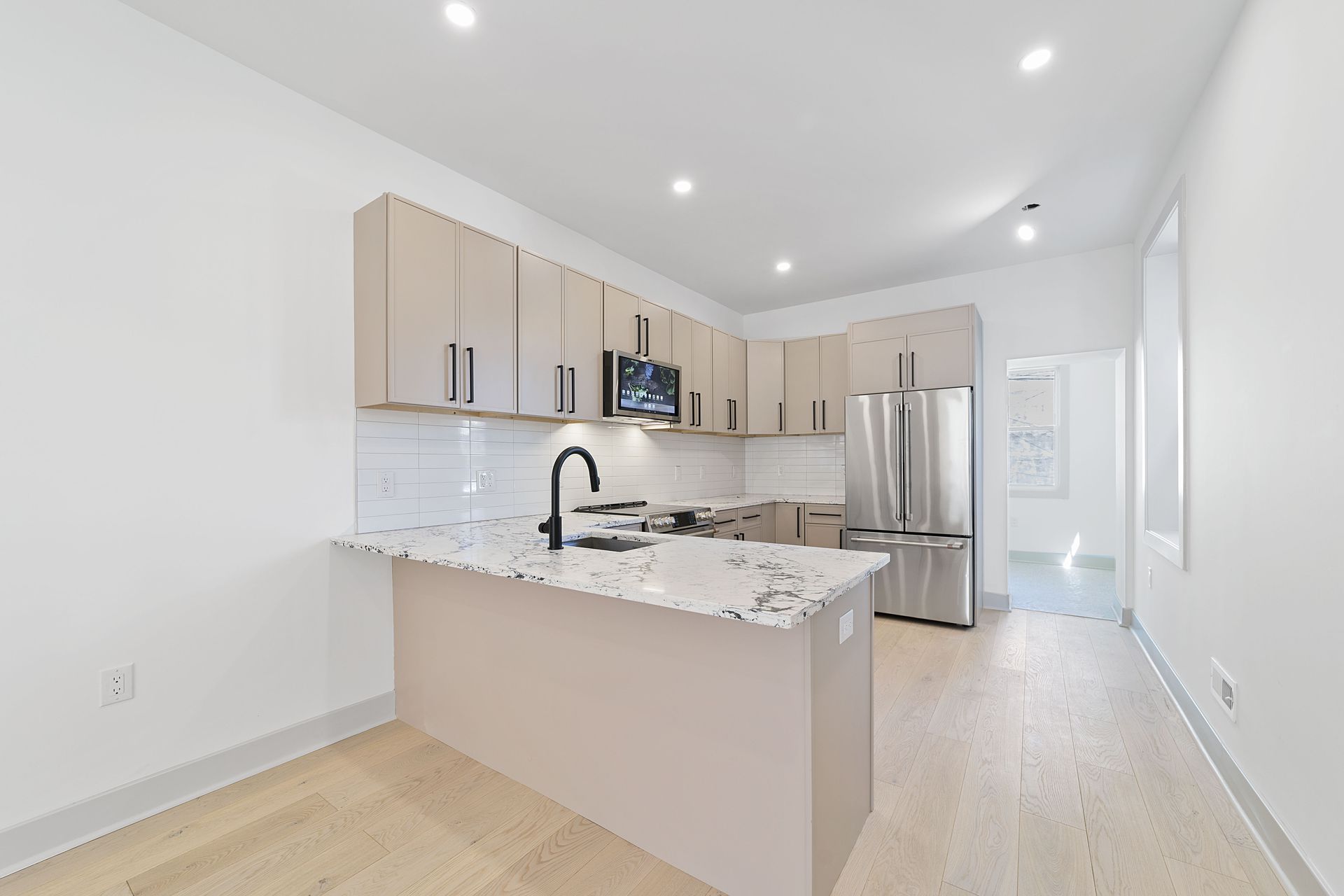 An empty kitchen with stainless steel appliances and marble counter tops.