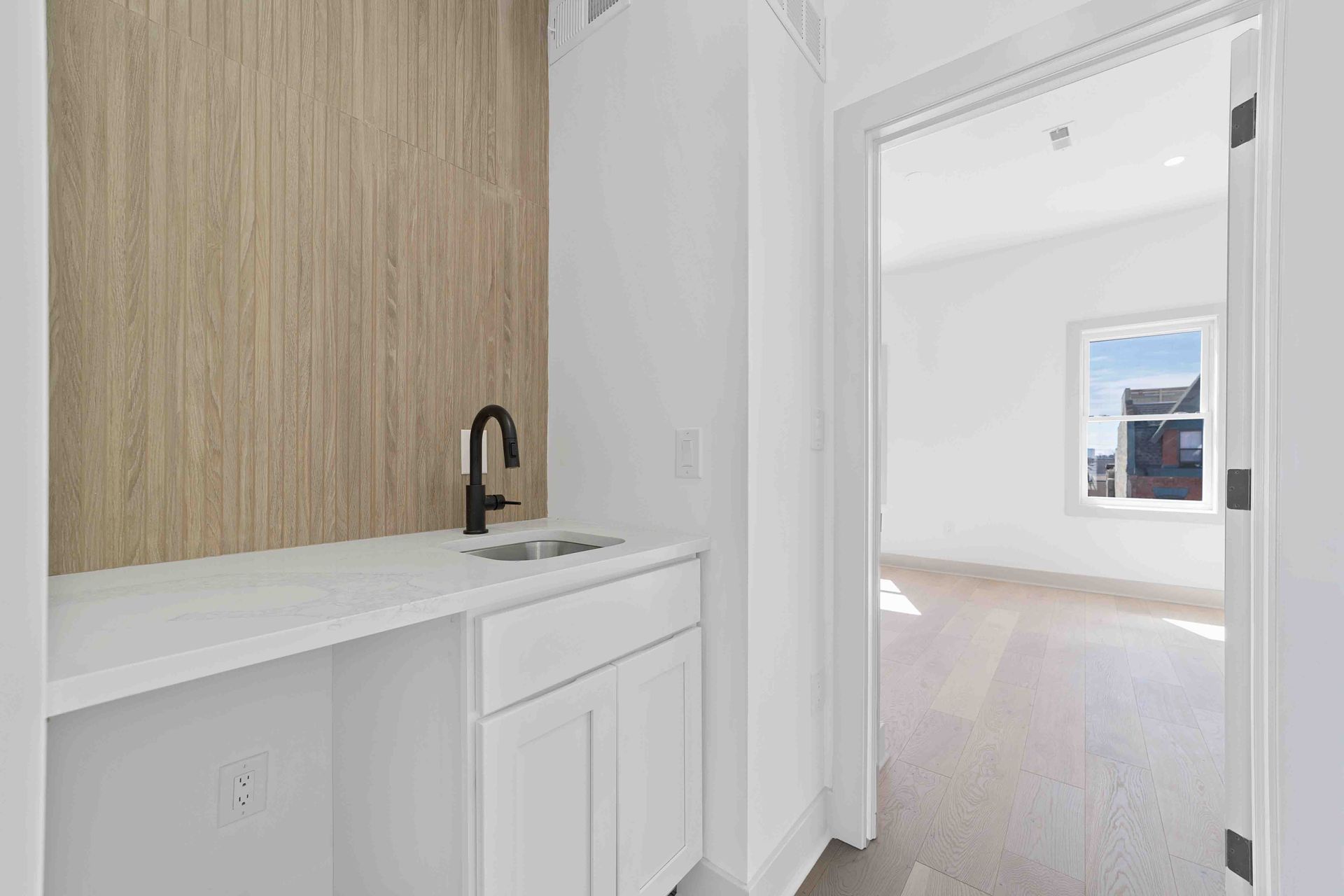 A kitchen with a sink , cabinets , and a wooden wall.
