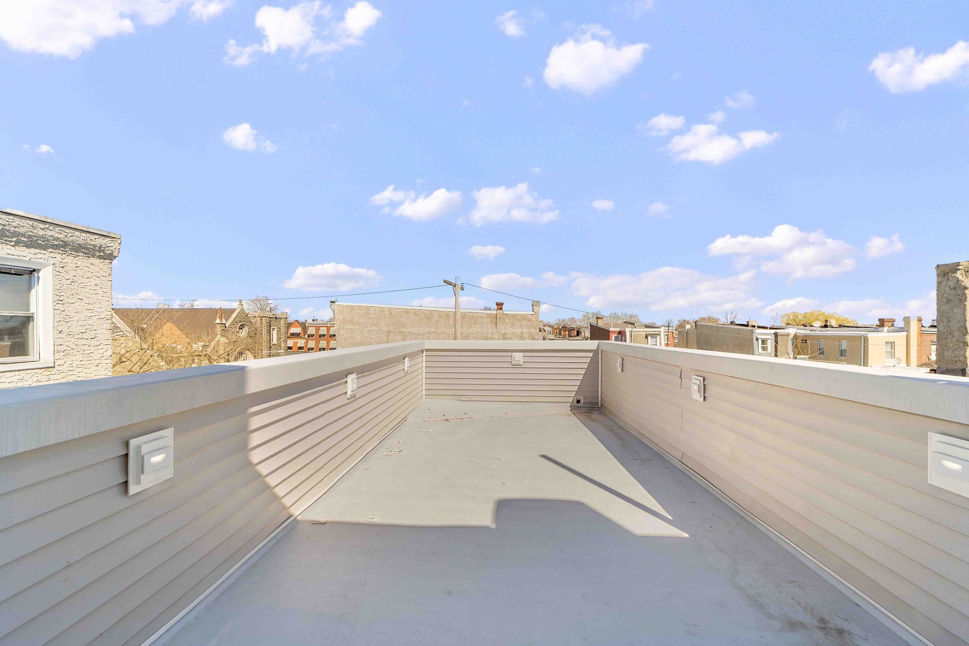 A rooftop deck with a view of a city on a sunny day