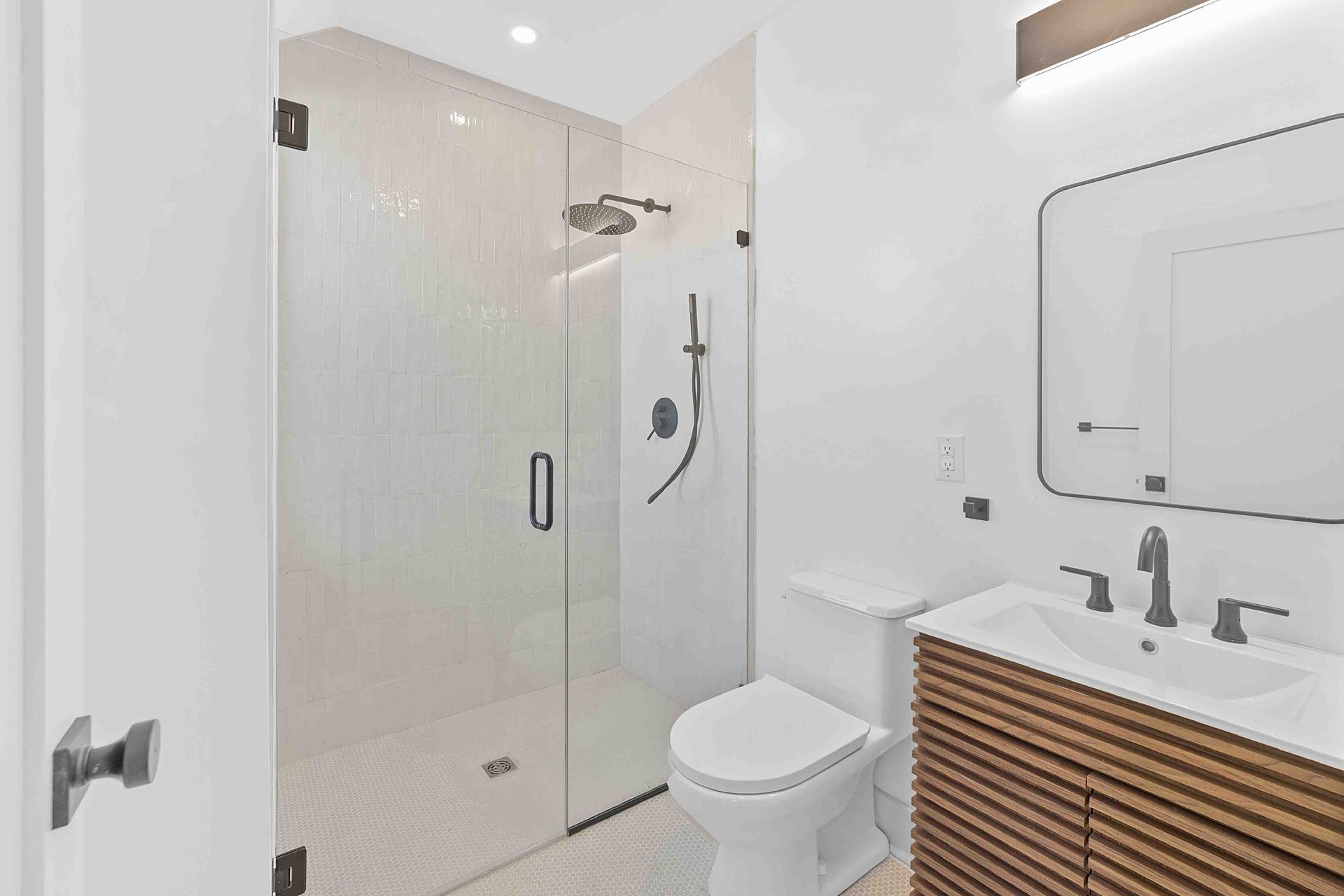 A bathroom with a toilet , sink , shower and mirror.