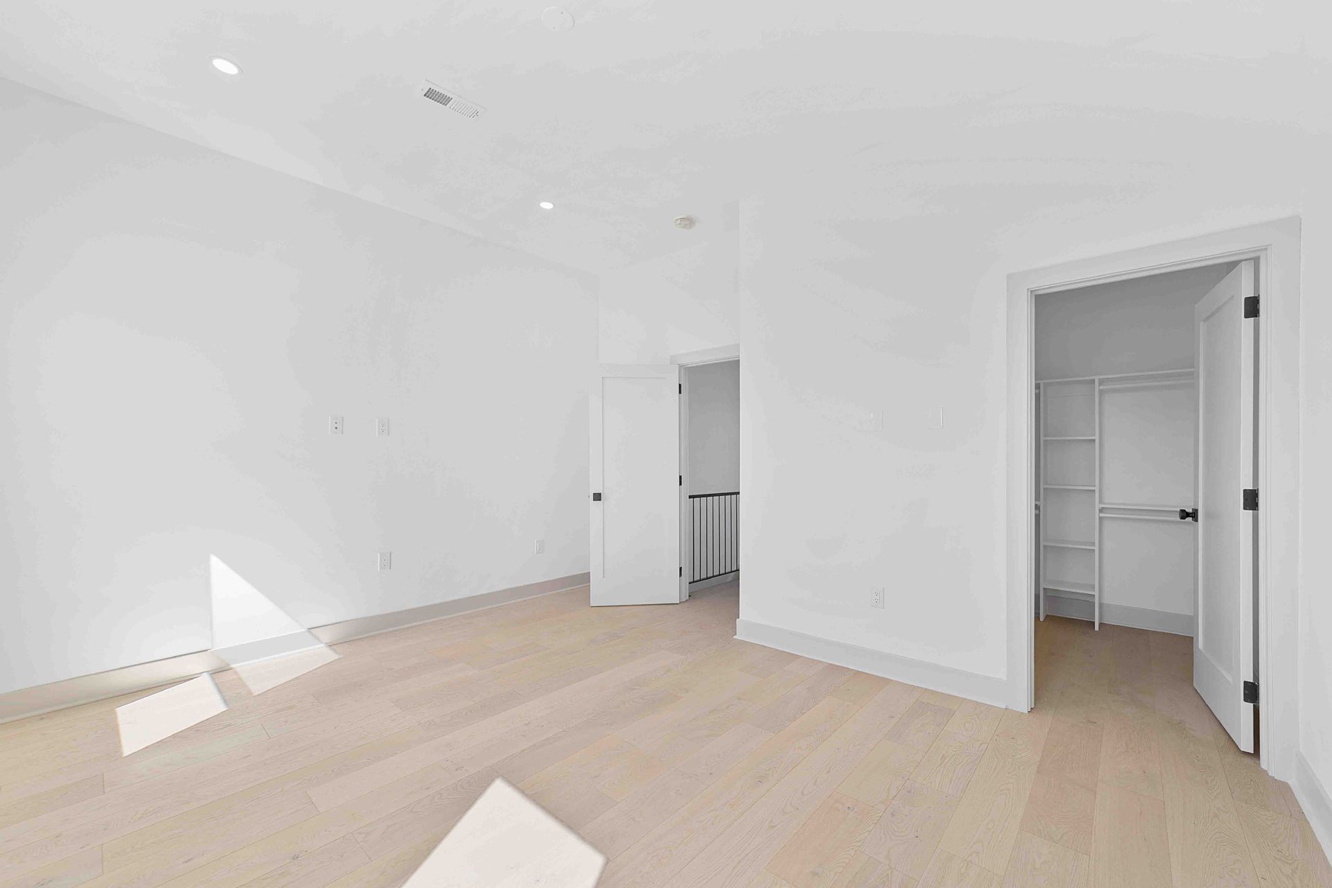A large empty room with hardwood floors and white walls.