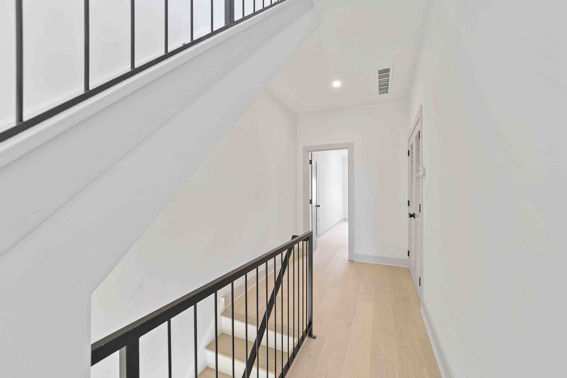 A hallway with stairs and a railing in a house.