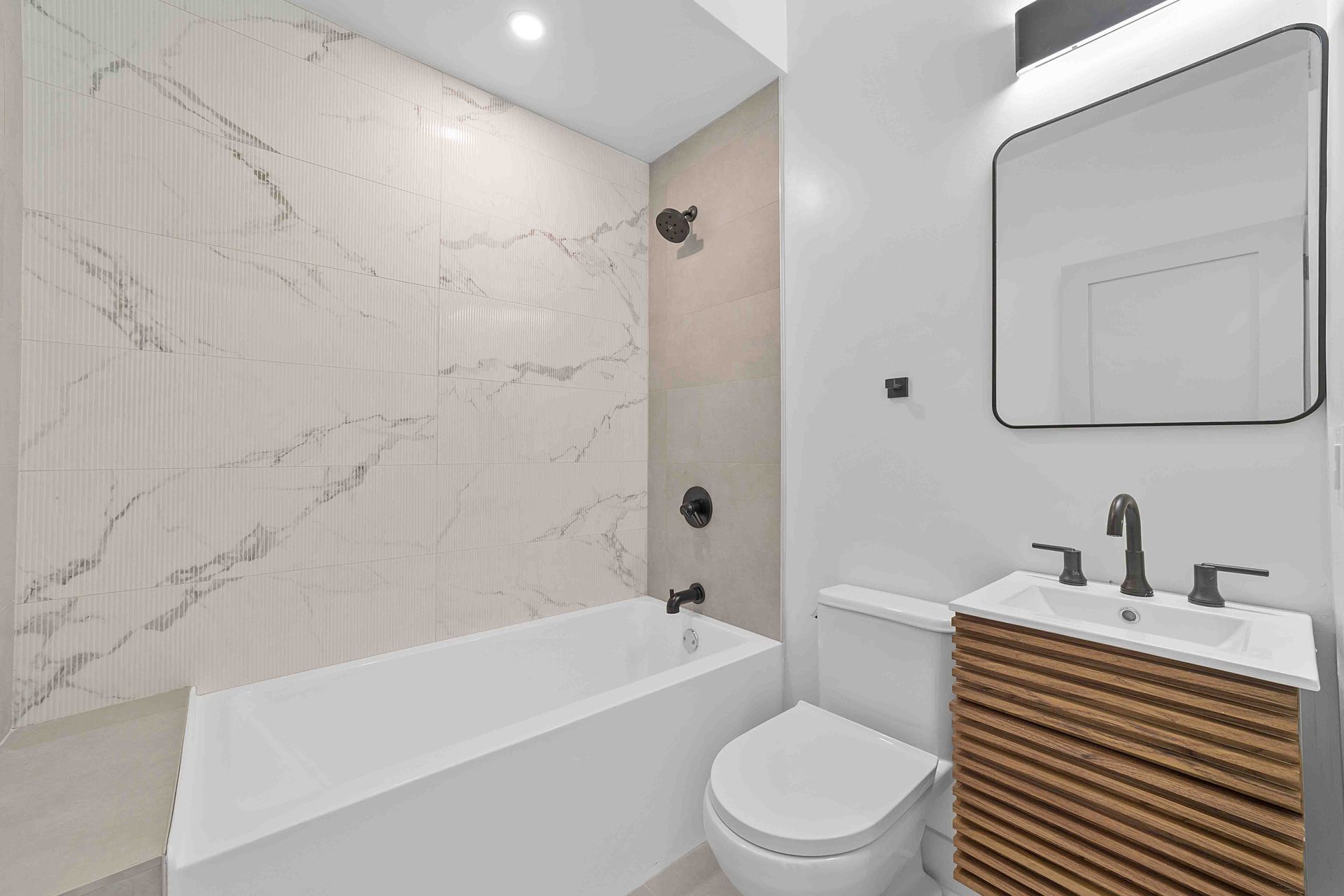 A bathroom with a tub , toilet , sink and mirror.