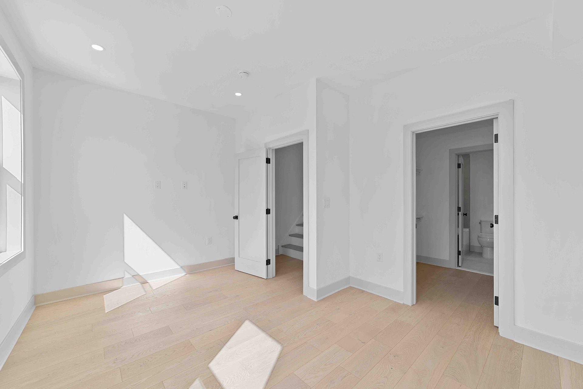 A large empty room with hardwood floors and white walls.